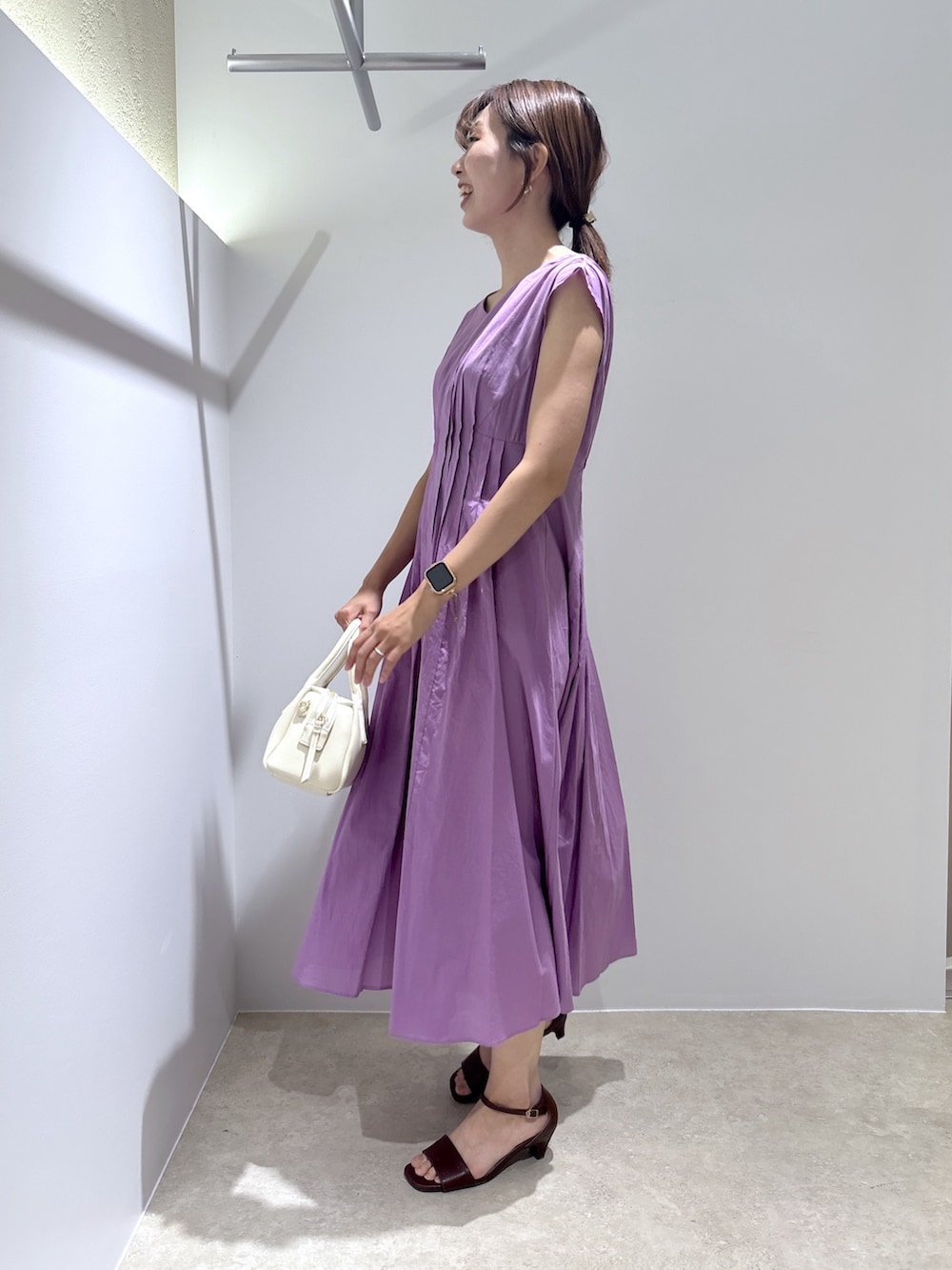 パープル系のワンピース、ホワイト系のボストンバッグ、ブラウン系のサンダルを着用したレディースの夏コーディネートの3枚目の写真