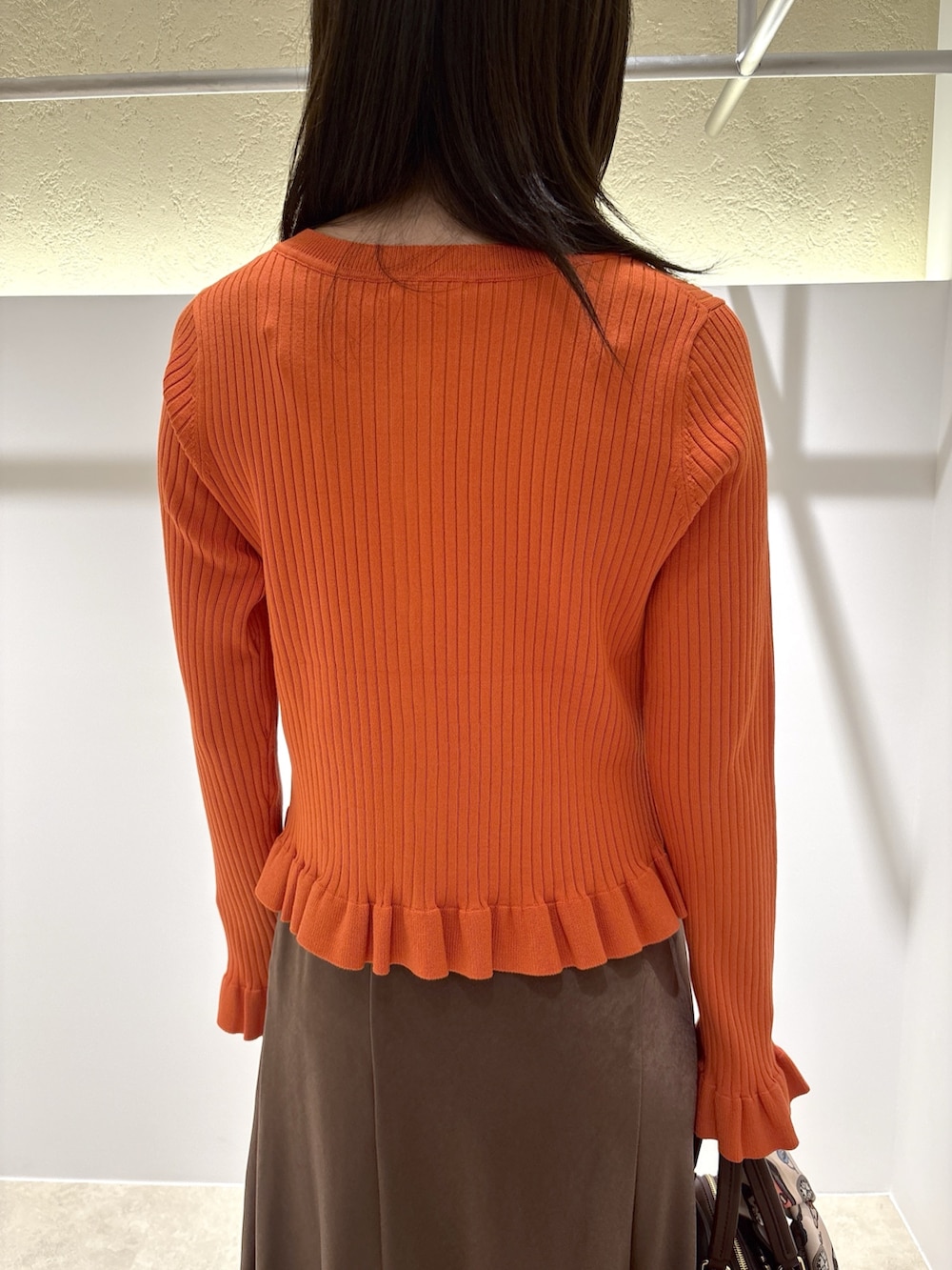 オレンジ系のニット/セーター、ブラウン系のスカート、レッド系のトートバッグを着用したレディースの夏コーディネートの8枚目の写真