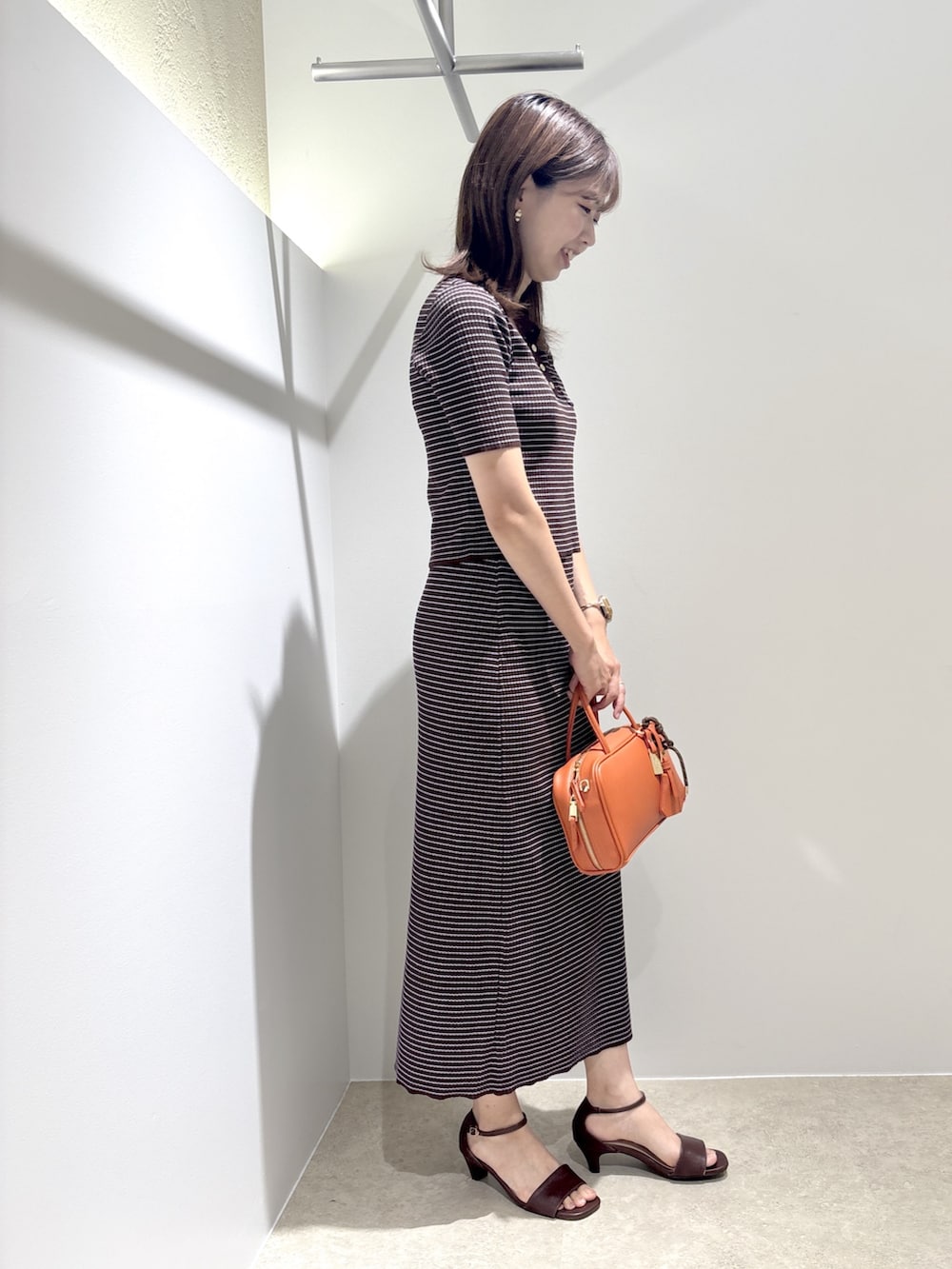 ブラウン系のワンピース、ブラウン系のサンダル、オレンジ系のボストンバッグを着用したレディースの夏コーディネートの5枚目の写真