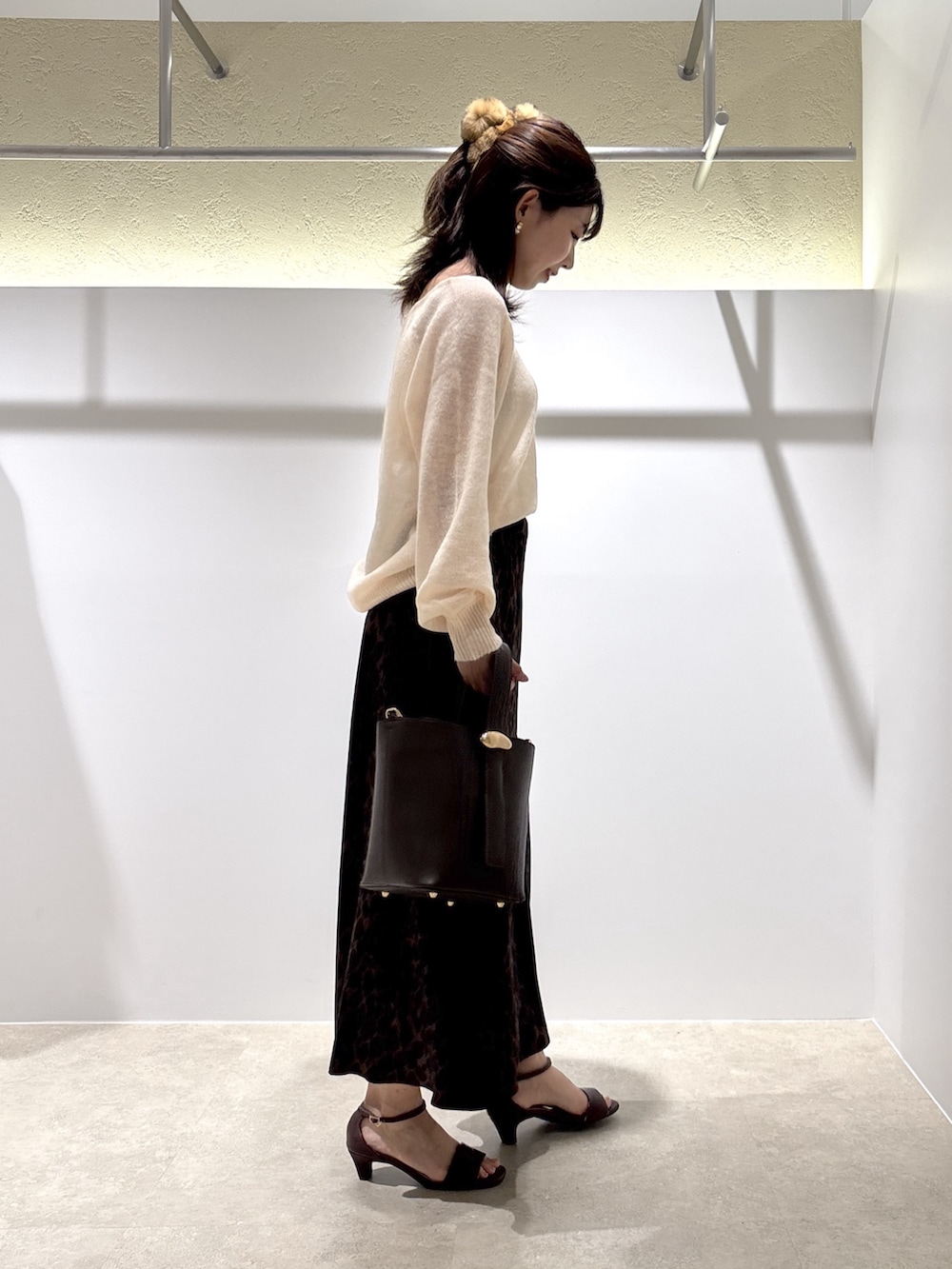 ベージュ系のニット/セーター、ブラウン系のスカート、ブラウン系のショルダーバッグを着用したレディースの夏コーディネートの3枚目の写真