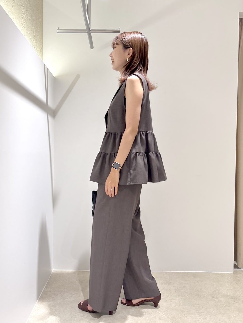 ブラウン系のベスト、ブラウン系のその他パンツ、ブラック系のショルダーバッグを着用したレディースの夏コーディネートの2枚目の写真