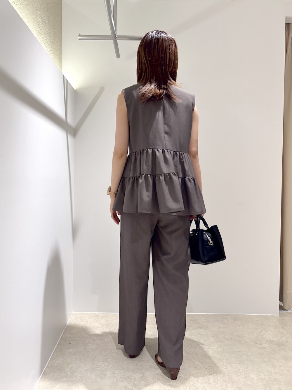 ブラウン系のベスト、ブラウン系のその他パンツ、ブラック系のショルダーバッグを着用したレディースの夏コーディネートの3枚目の写真