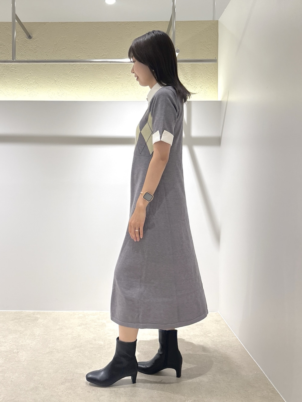 グレー系のワンピース、ブラック系のブーツ、ブラック系のトートバッグを着用したレディースの夏コーディネートの2枚目の写真