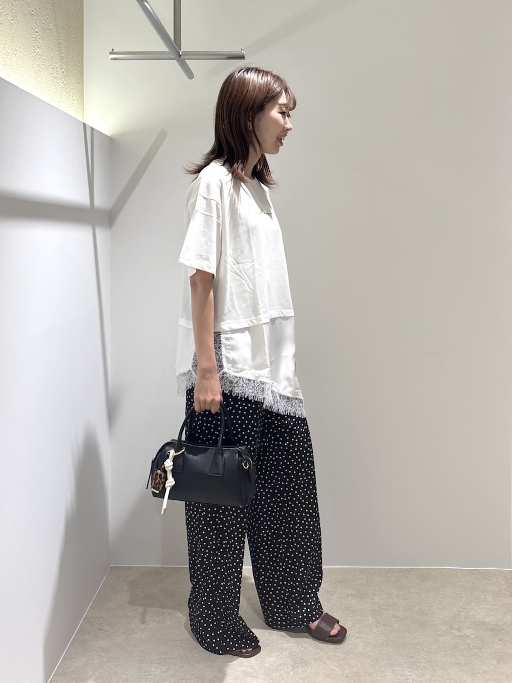 ホワイト系のTシャツ/カットソー、ブラック系のサンダル、ブラック系のボストンバッグを着用したレディースの夏コーディネートの4枚目の写真