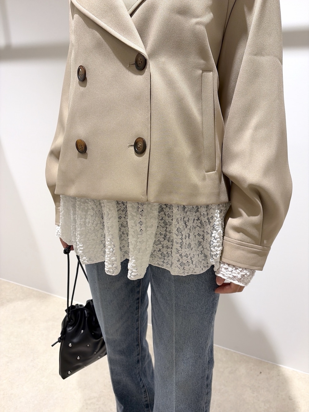 ベージュ系のトレンチコート、ホワイト系のTシャツ/カットソー、ブラック系のデニムパンツを着用したレディースの秋コーディネートの6枚目の写真
