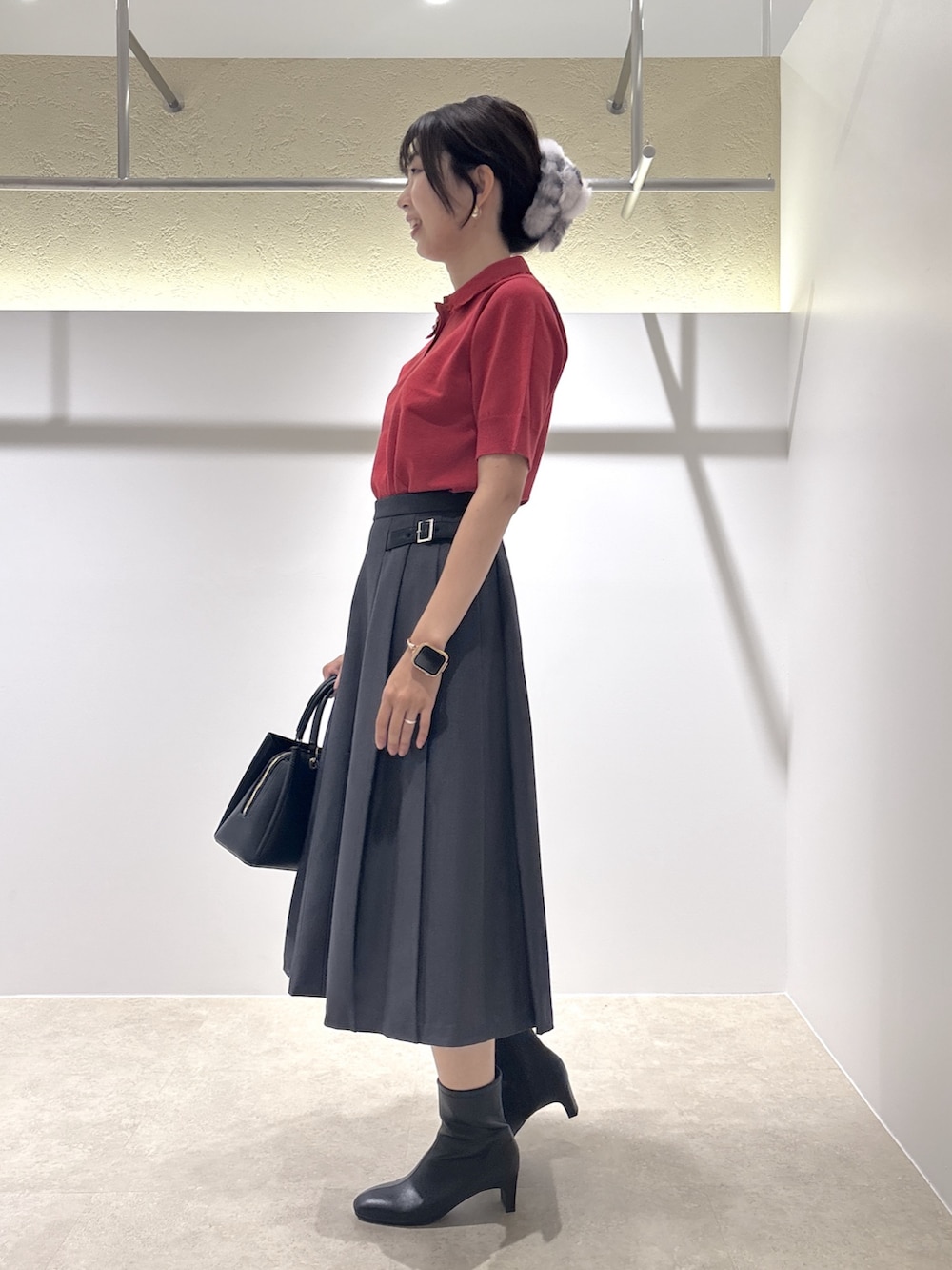 レッド系のニット/セーター、グレー系のスカート、ブラック系のブーツを着用したレディースの夏コーディネートの2枚目の写真