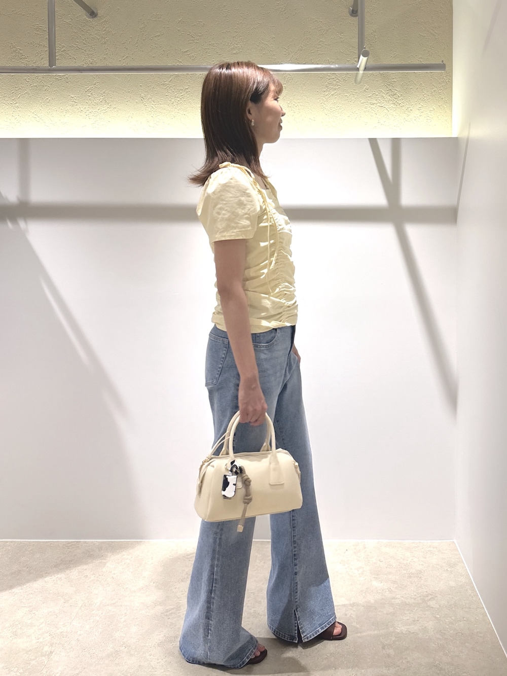 イエロー系のTシャツ/カットソー、ブルー系のデニムパンツ、ブラウン系のサンダルを着用したレディースの夏コーディネートの3枚目の写真