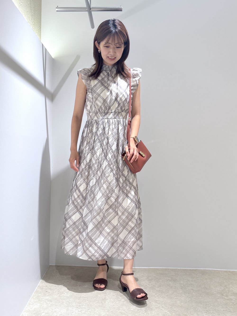 ベージュ系のワンピース、レッド系のショルダーバッグ、ブラウン系のサンダルを着用したレディースの夏コーディネートの2枚目の写真