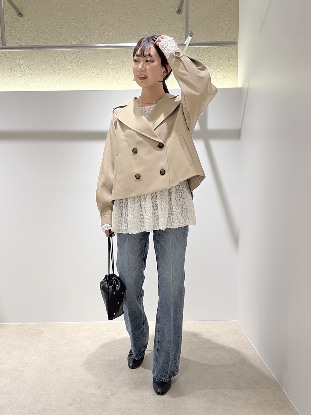 ベージュ系のトレンチコート、ホワイト系のTシャツ/カットソー、ブラック系のデニムパンツを着用したレディースの秋コーディネートの5枚目の写真
