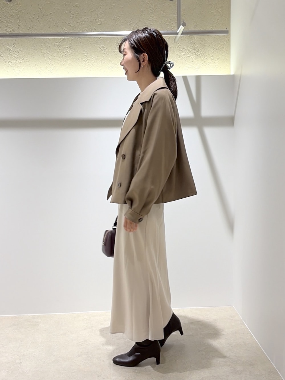 ホワイト系のTシャツ/カットソー、ブラウン系のトレンチコート、ホワイト系のスカートを着用したレディースの秋コーディネートの2枚目の写真