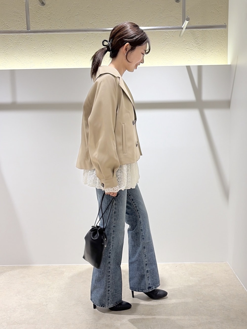 ベージュ系のトレンチコート、ホワイト系のTシャツ/カットソー、ブラック系のデニムパンツを着用したレディースの秋コーディネートの4枚目の写真