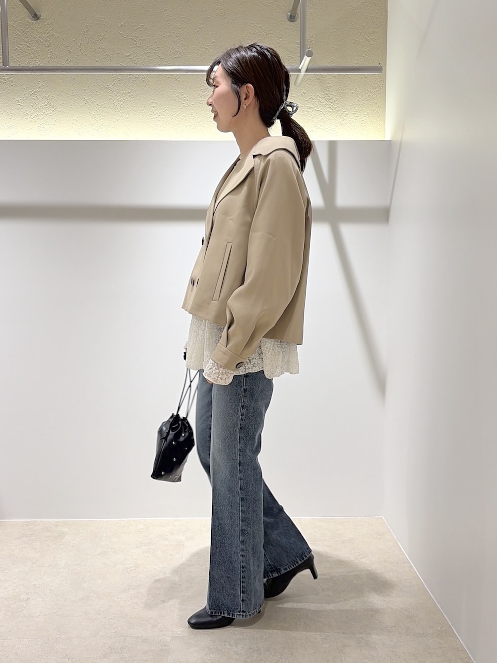 ベージュ系のトレンチコート、ホワイト系のTシャツ/カットソー、ブラック系のデニムパンツを着用したレディースの秋コーディネートの2枚目の写真