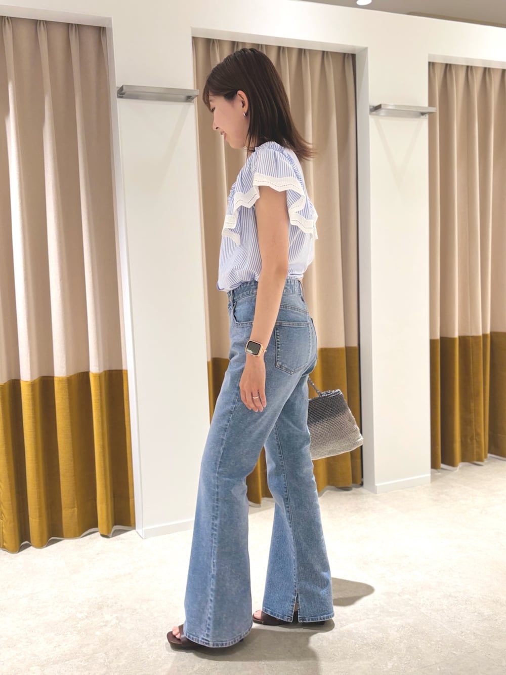 ブラウン系のサンダル、ブルー系のデニムパンツ、シルバー系のハンドバッグを着用したレディースの夏コーディネートの2枚目の写真