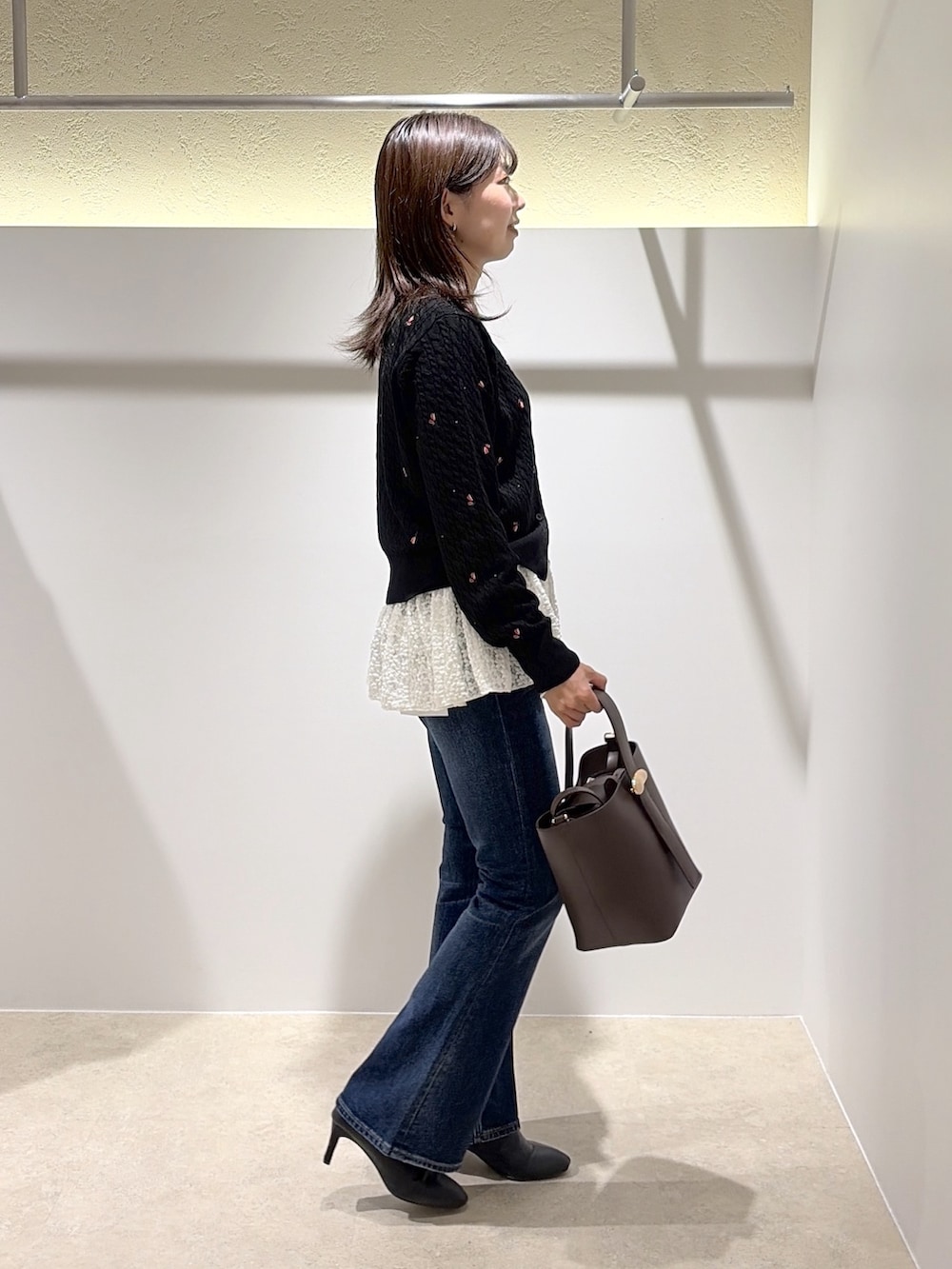 ブラック系のカーディガン/ボレロ、ホワイト系のTシャツ/カットソー、ブルー系のデニムパンツを着用したレディースの秋コーディネートの3枚目の写真