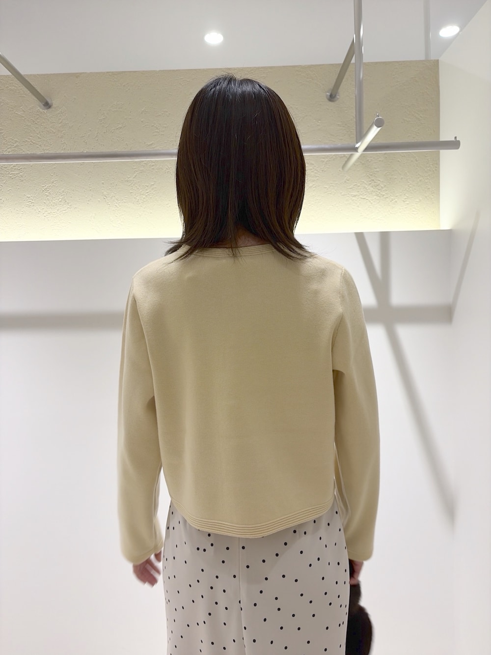 イエロー系のカーディガン/ボレロ、ホワイト系のスカート、ブラウン系のブーツを着用したレディースの秋コーディネートの8枚目の写真