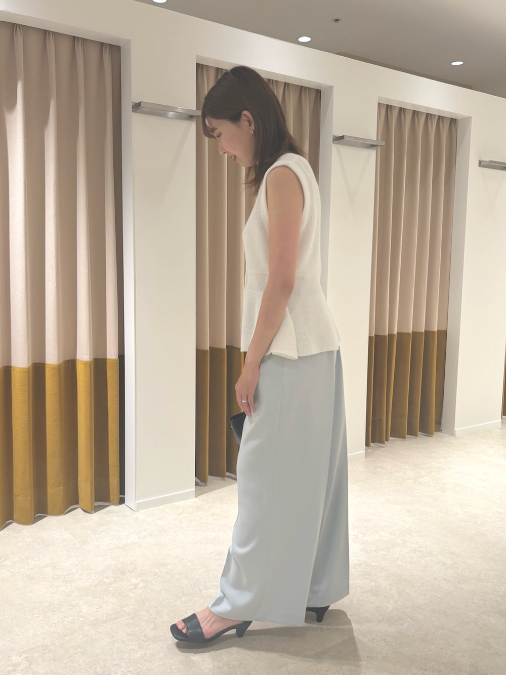 ホワイト系のベスト、ブルー系のその他パンツ、ブラック系のサンダルを着用したレディースの夏コーディネートの2枚目の写真