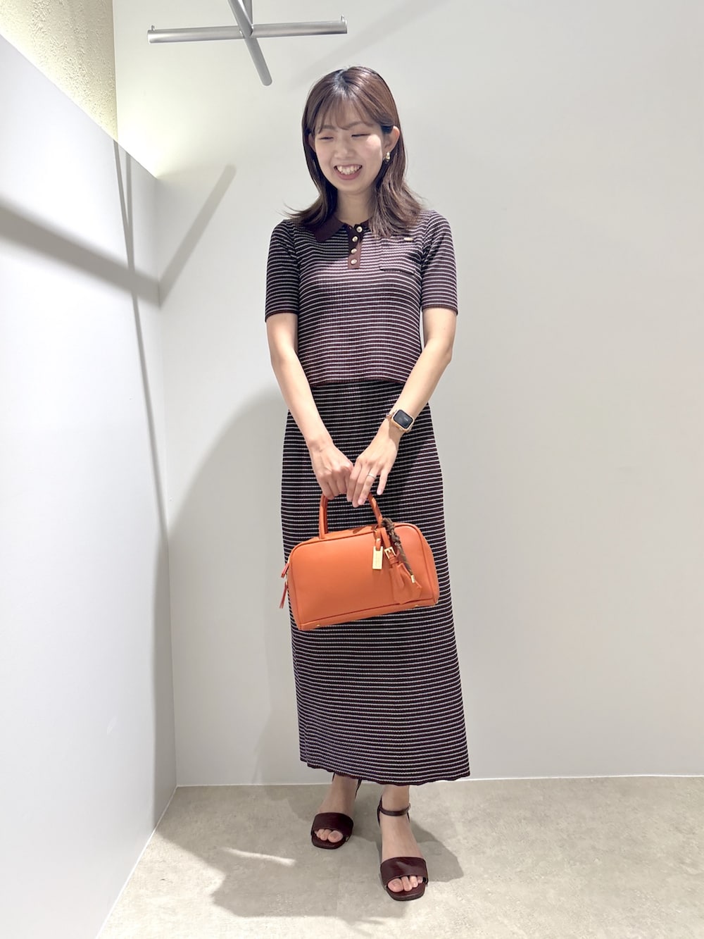 ブラウン系のワンピース、ブラウン系のサンダル、オレンジ系のボストンバッグを着用したレディースの夏コーディネートの2枚目の写真