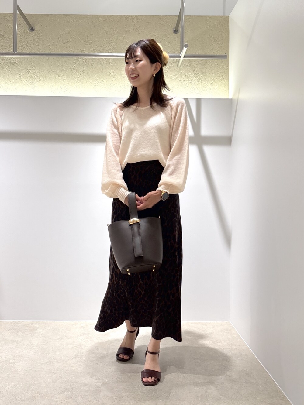 ベージュ系のニット/セーター、ブラウン系のスカート、ブラウン系のショルダーバッグを着用したレディースの夏コーディネートの2枚目の写真