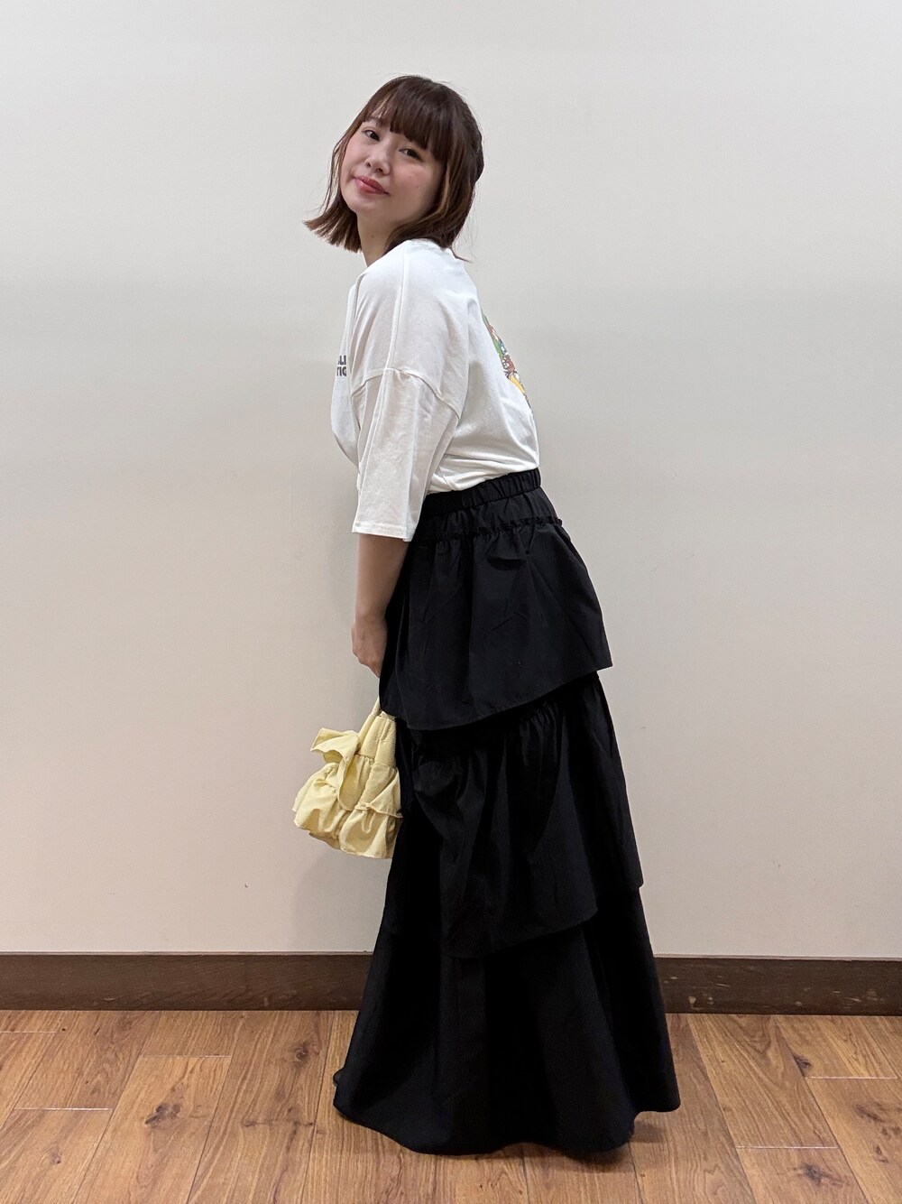 ホワイト系のTシャツ/カットソー、ブラック系のスカート、イエロー系のショルダーバッグを着用したレディースの春コーディネートの2枚目の写真