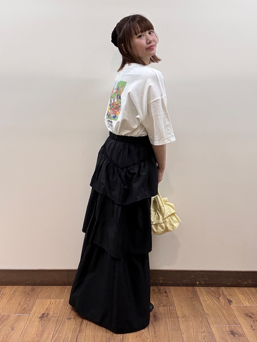 ホワイト系のTシャツ/カットソー、ブラック系のスカート、イエロー系のショルダーバッグを着用したレディースの春コーディネートの4枚目の写真