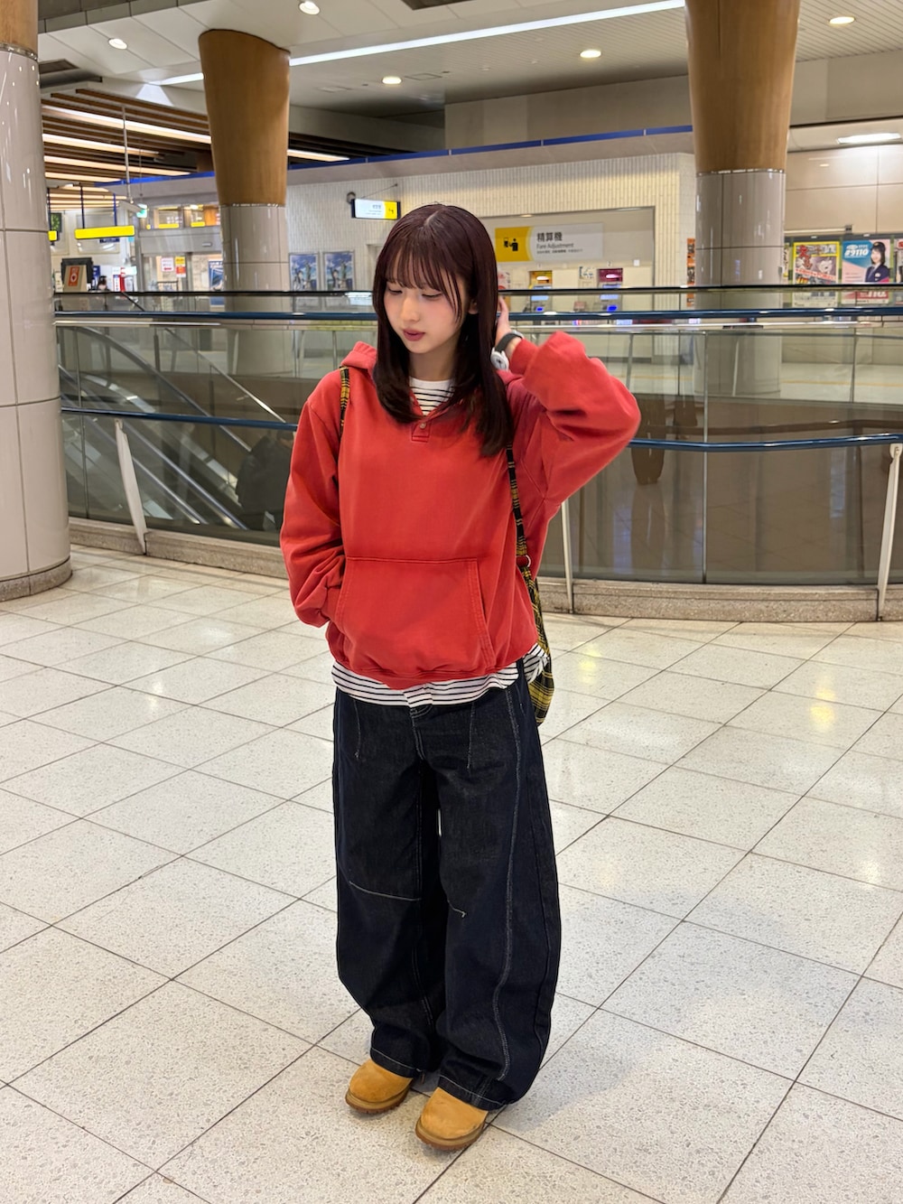 レッド系のパーカー、ブルー系のデニムパンツ、イエロー系のブーツを着用したレディースの春コーディネートの4枚目の写真