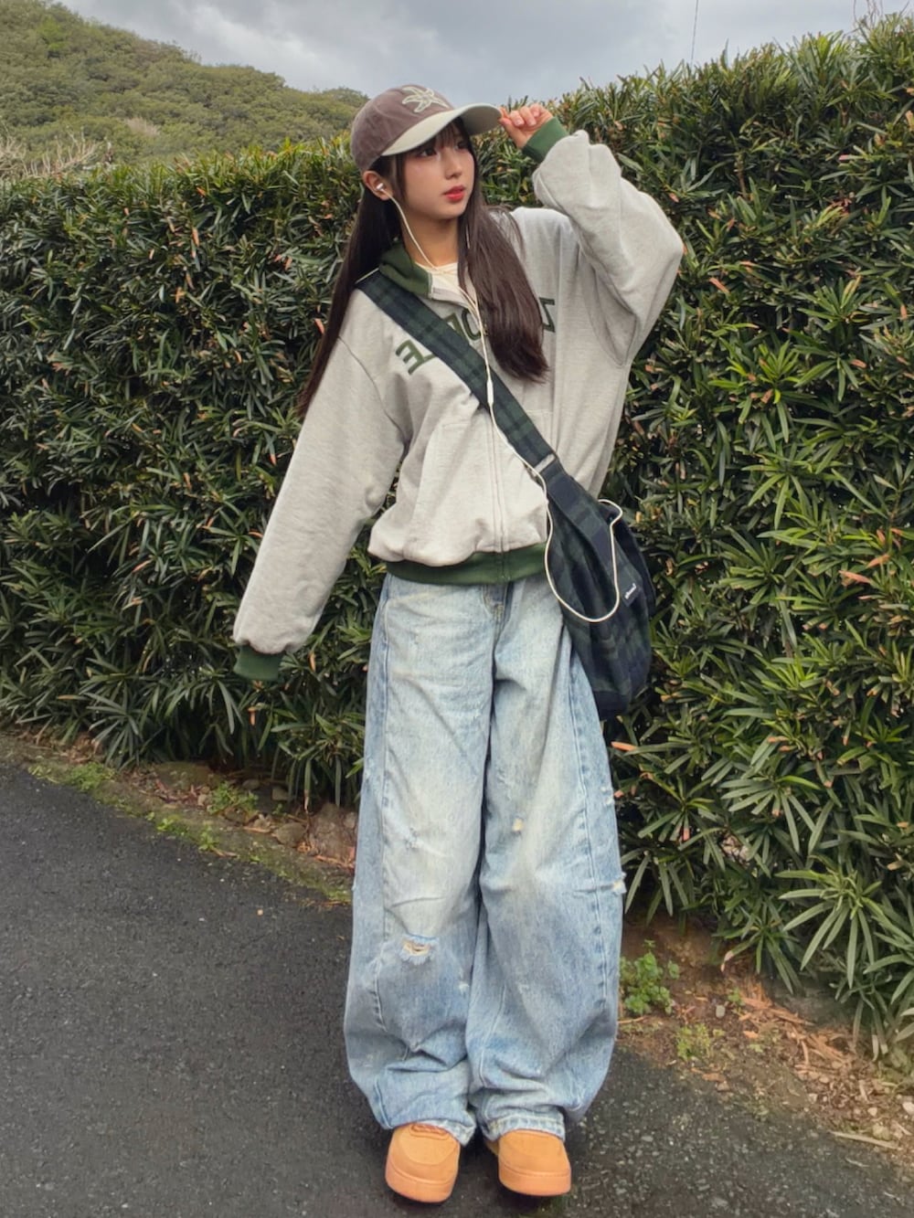 グレー系のパーカー、グリーン系のボストンバッグ、ブルー系のデニムパンツを着用したレディースの春コーディネートの2枚目の写真