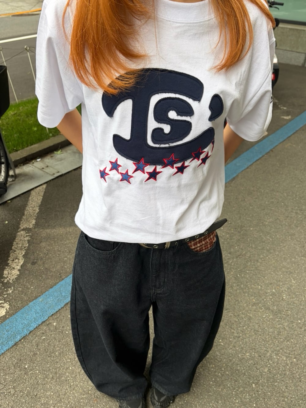 ブラック系のスニーカー、ホワイト系のTシャツ/カットソー、ブラック系のデニムパンツを着用したレディースの春コーディネートの4枚目の写真