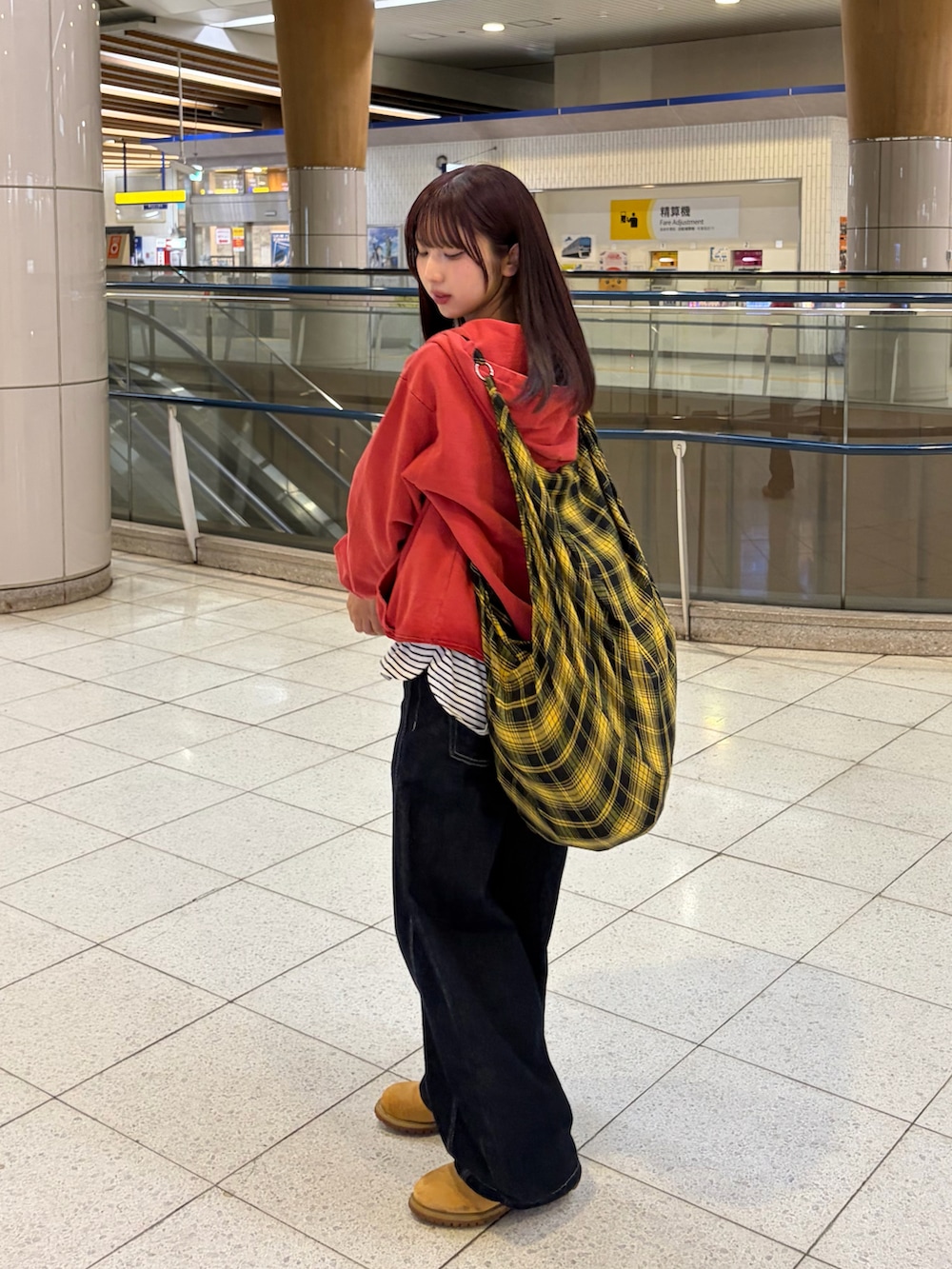 レッド系のパーカー、ブルー系のデニムパンツ、イエロー系のブーツを着用したレディースの春コーディネートの5枚目の写真