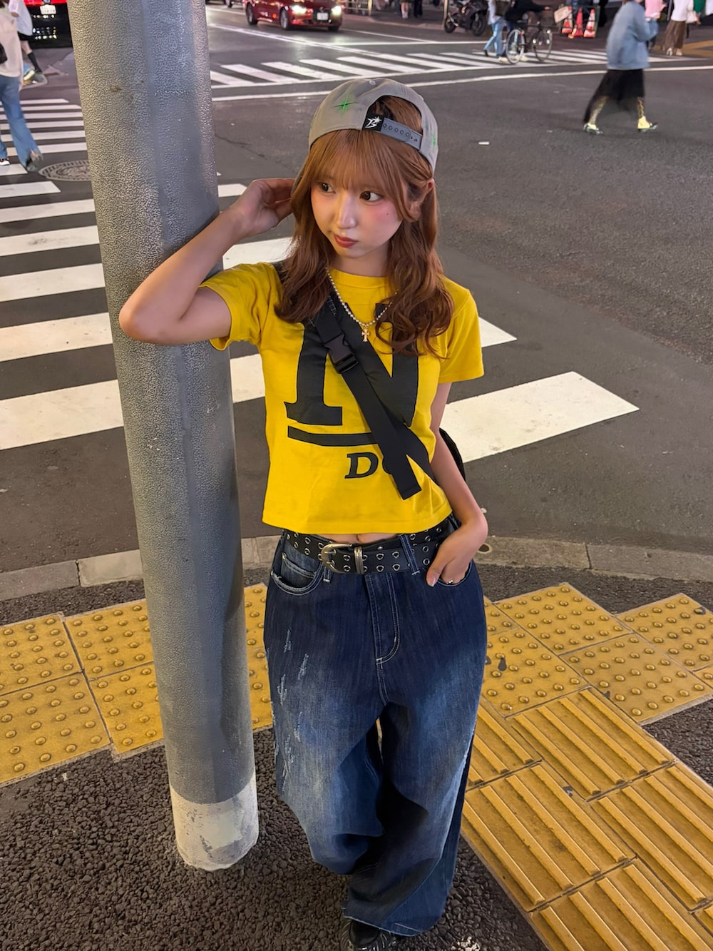イエロー系のトップス、ブルー系のデニムパンツ、ブラック系のスニーカーを着用したレディースの夏コーディネートの2枚目の写真