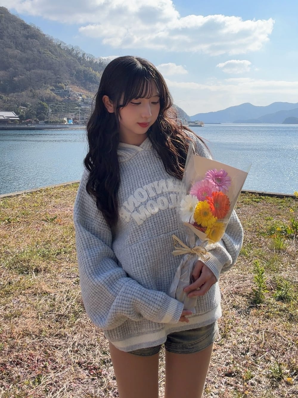 グレー系のニット/セーター、イエロー系のブーツ、ブルー系のデニムパンツを着用したレディースの春コーディネートの4枚目の写真