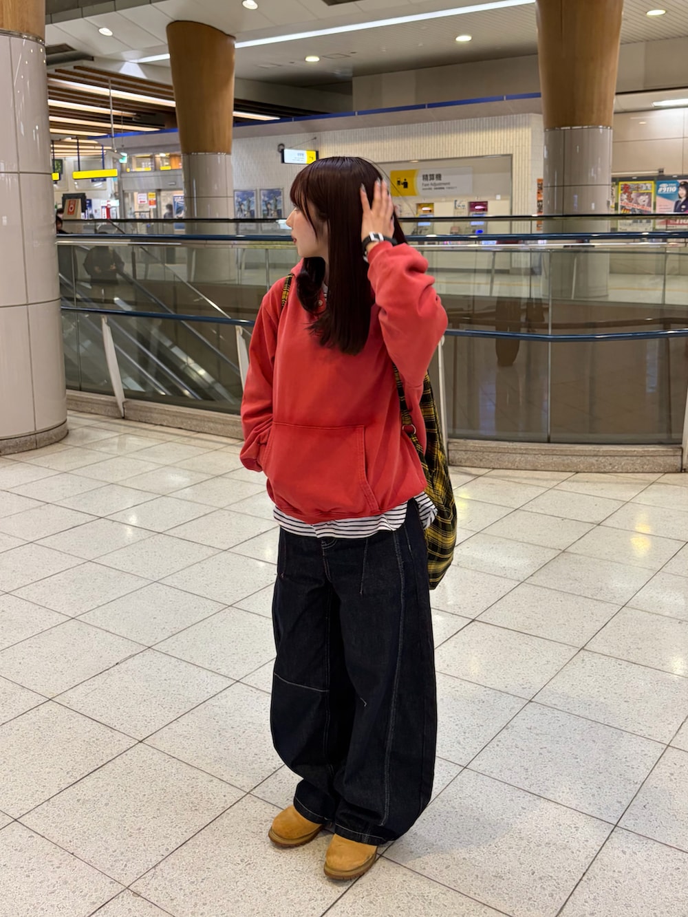 レッド系のパーカー、ブルー系のデニムパンツ、イエロー系のブーツを着用したレディースの春コーディネートの2枚目の写真