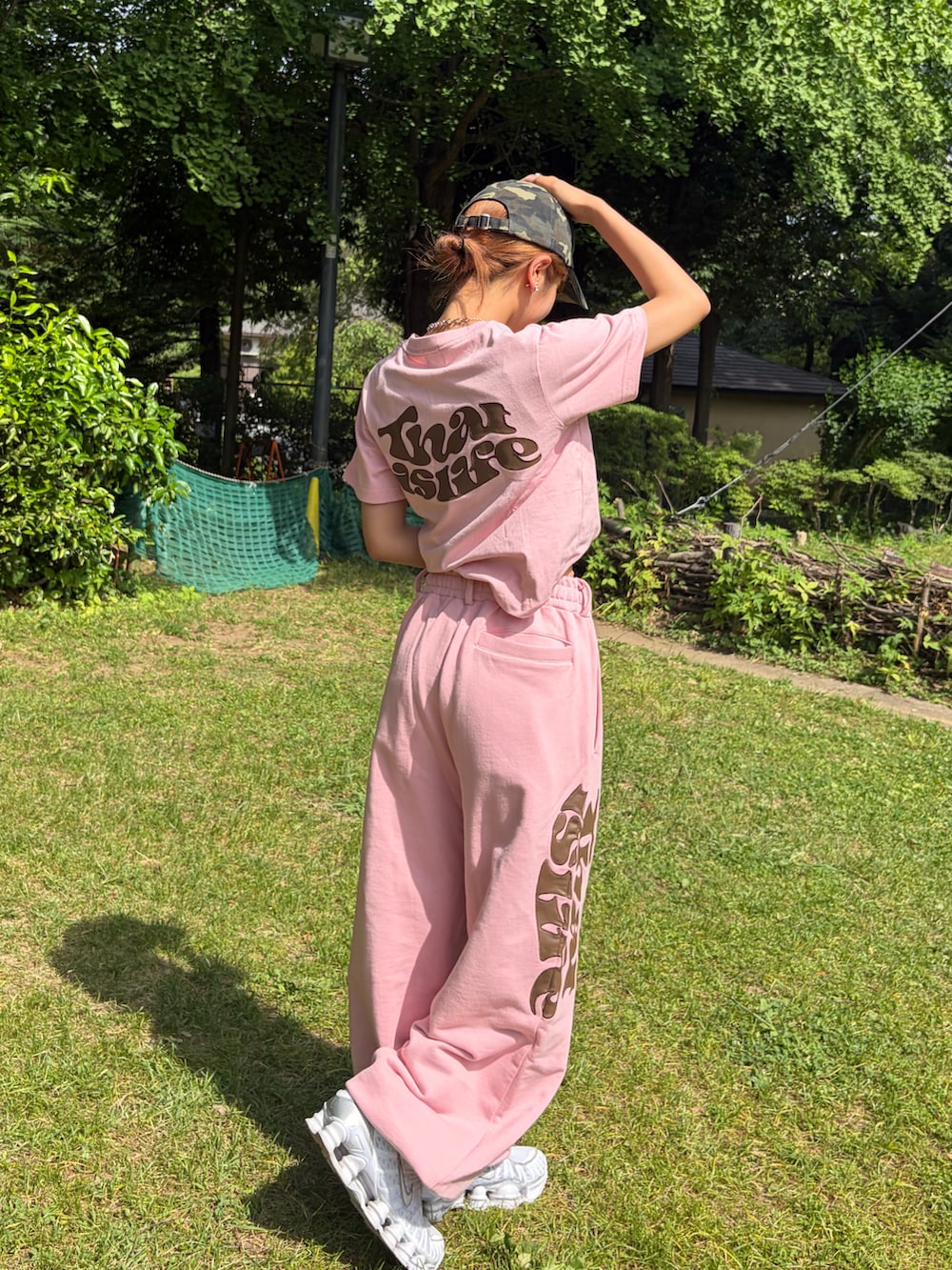 ピンク系のスウェットパンツ、ピンク系のTシャツ/カットソー、ホワイト系のスニーカーを着用したレディースの夏コーディネートの3枚目の写真