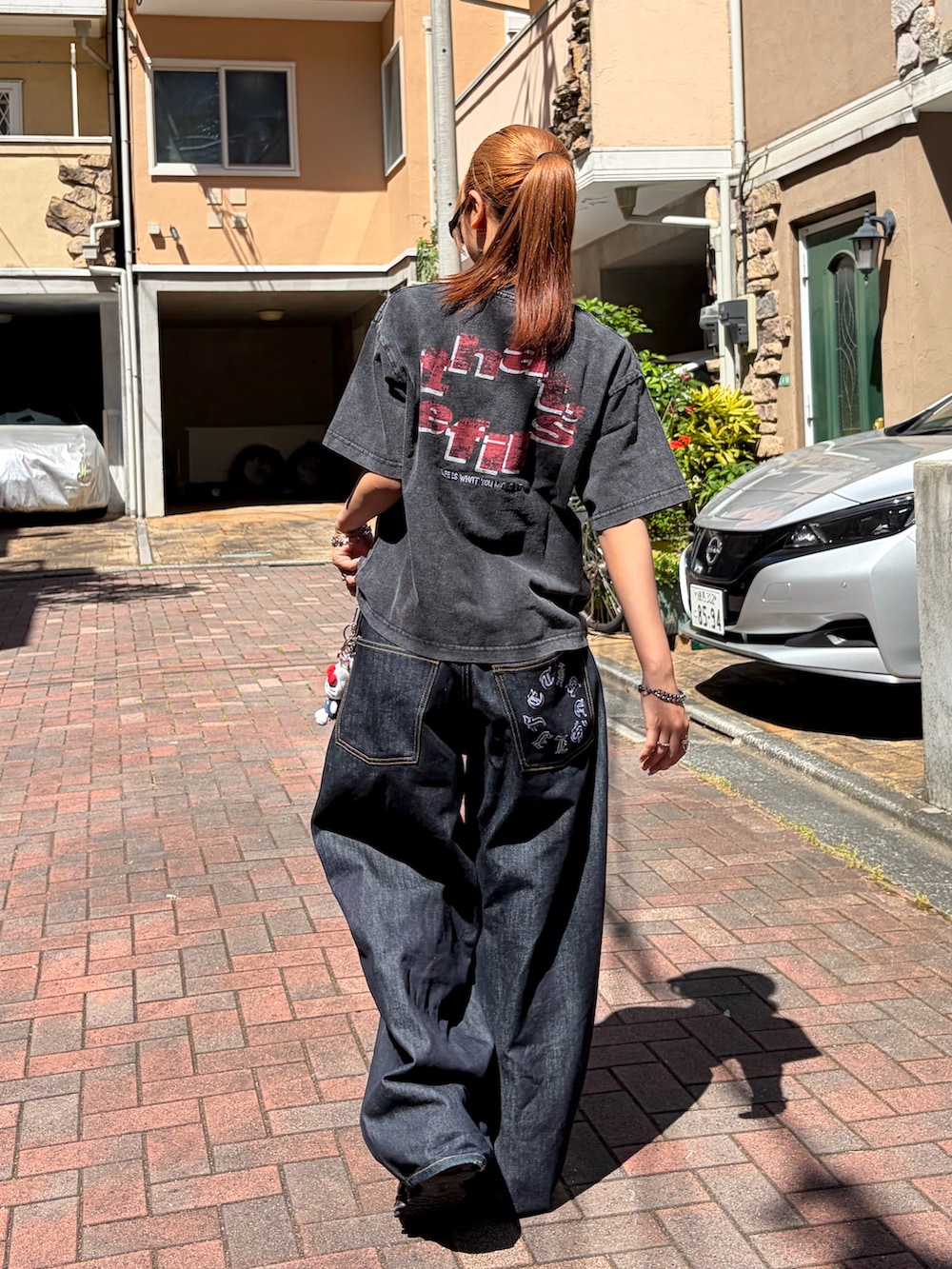 ブラック系のTシャツ/カットソー、ブラック系のデニムパンツ、ブラック系のスニーカーを着用したレディースの夏コーディネートの2枚目の写真