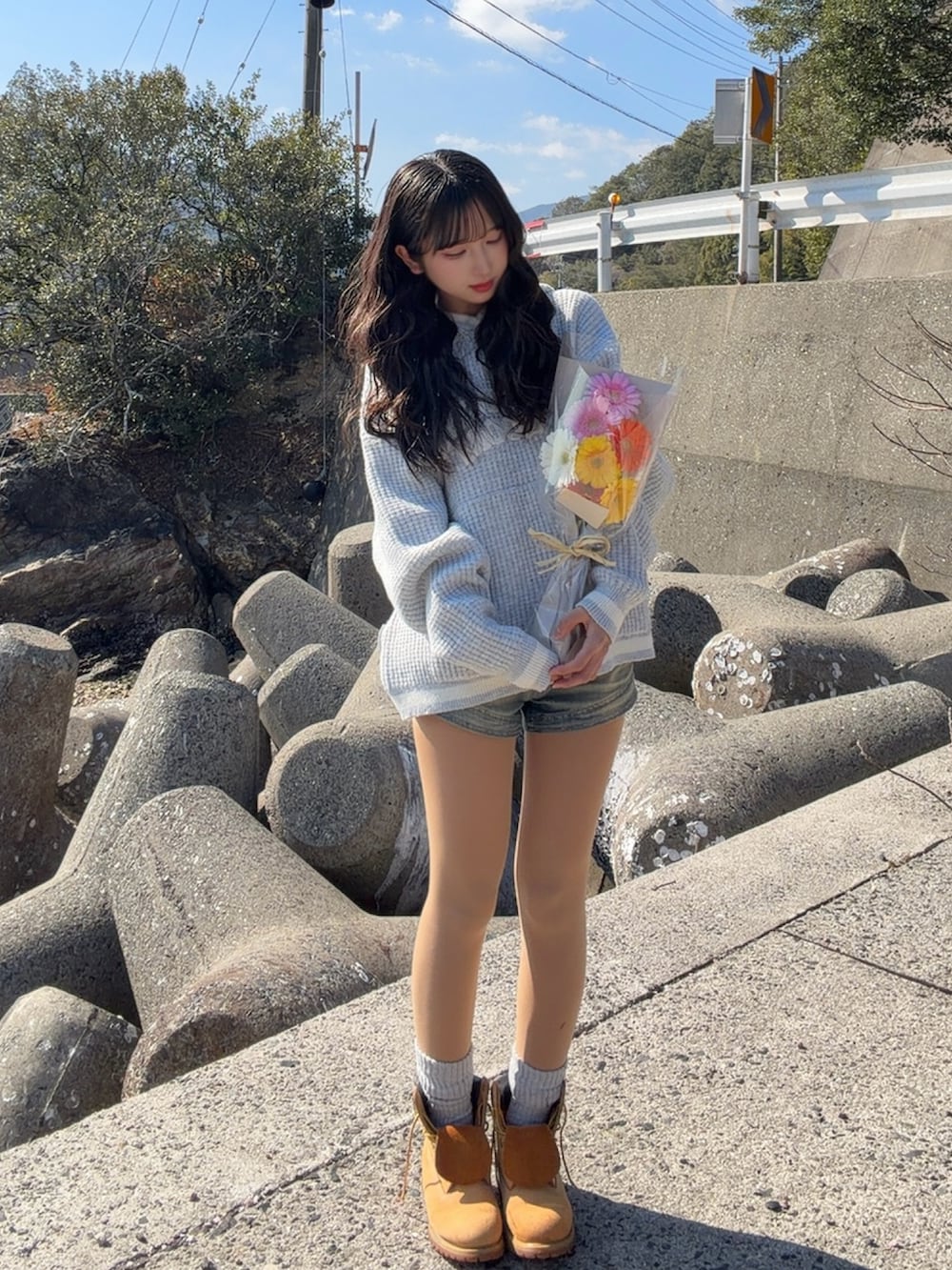 グレー系のニット/セーター、イエロー系のブーツ、ブルー系のデニムパンツを着用したレディースの春コーディネートの2枚目の写真