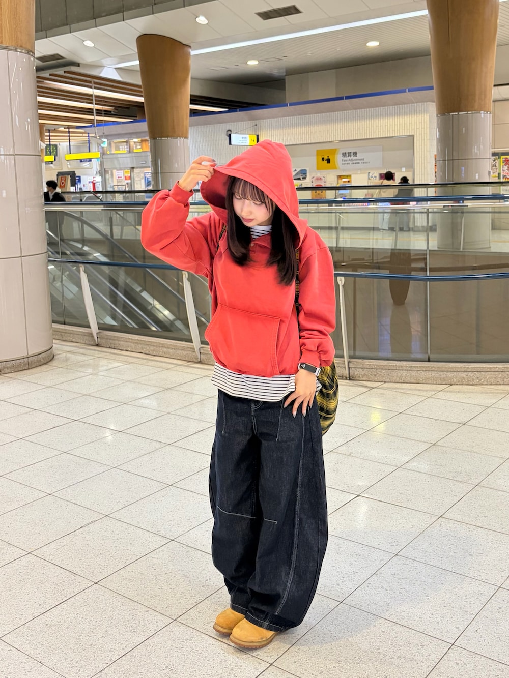 レッド系のパーカー、ブルー系のデニムパンツ、イエロー系のブーツを着用したレディースの春コーディネートの3枚目の写真