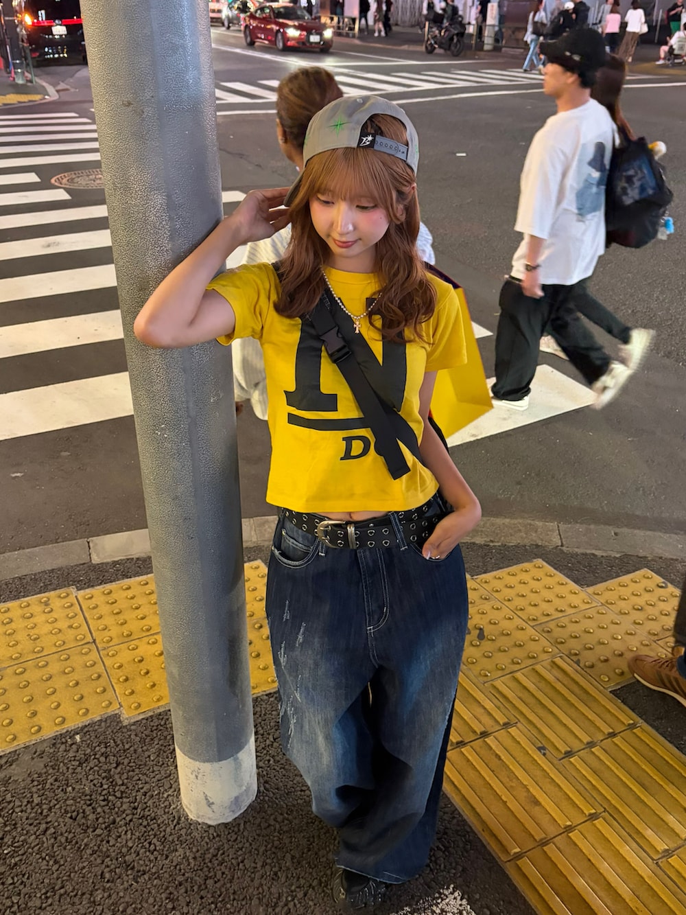 イエロー系のトップス、ブルー系のデニムパンツ、ブラック系のスニーカーを着用したレディースの夏コーディネートの3枚目の写真