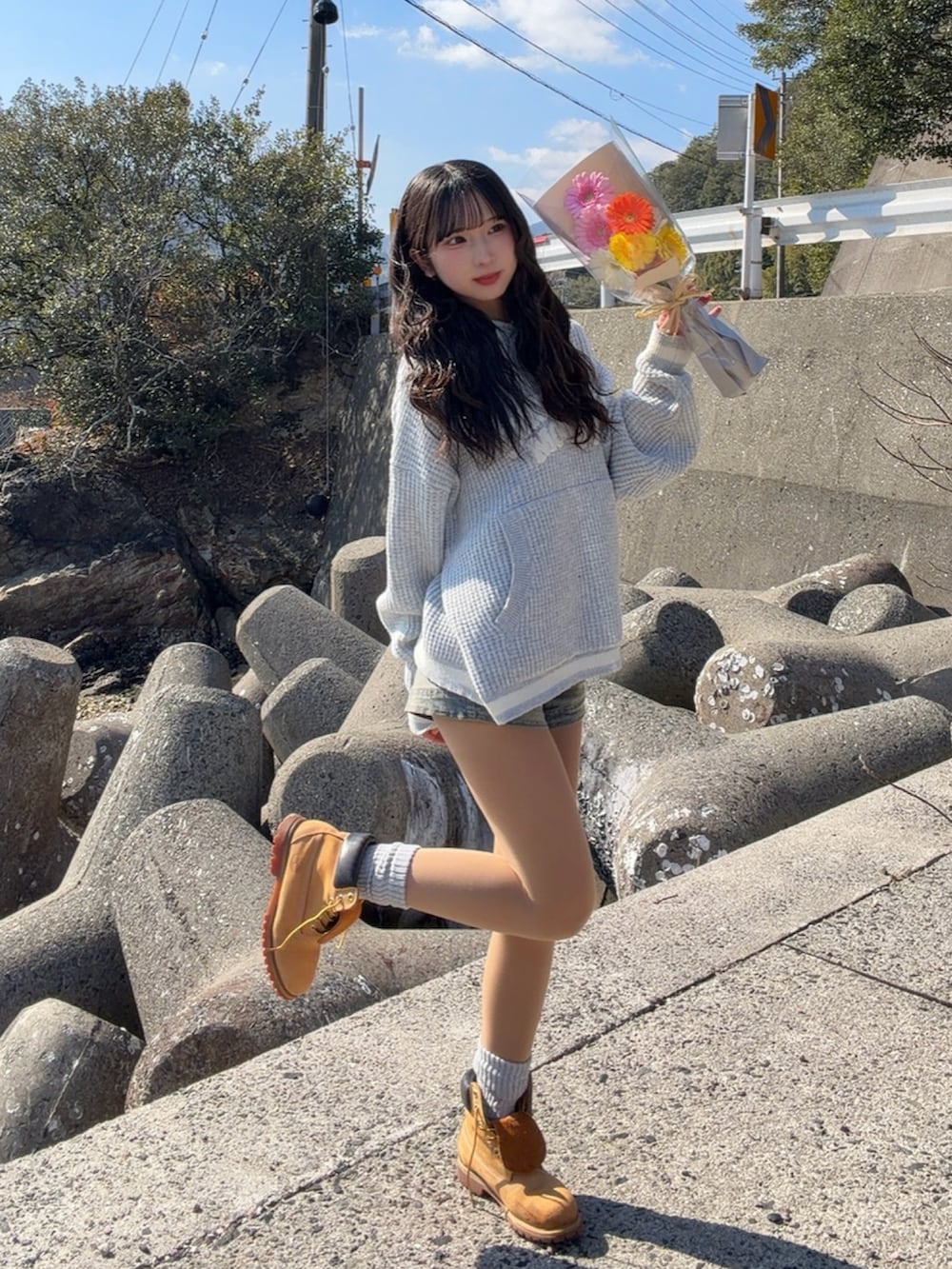 グレー系のニット/セーター、イエロー系のブーツ、ブルー系のデニムパンツを着用したレディースの春コーディネートの3枚目の写真