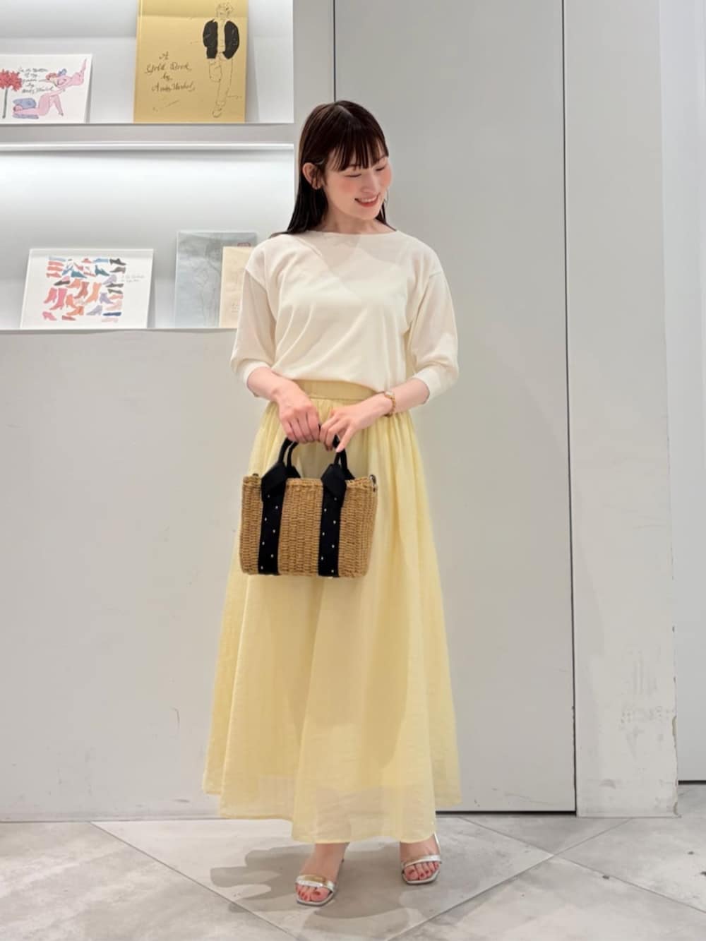 ブラック系のかごバッグ、ホワイト系のニット/セーター、イエロー系のスカートを着用したレディースの夏コーディネートの2枚目の写真
