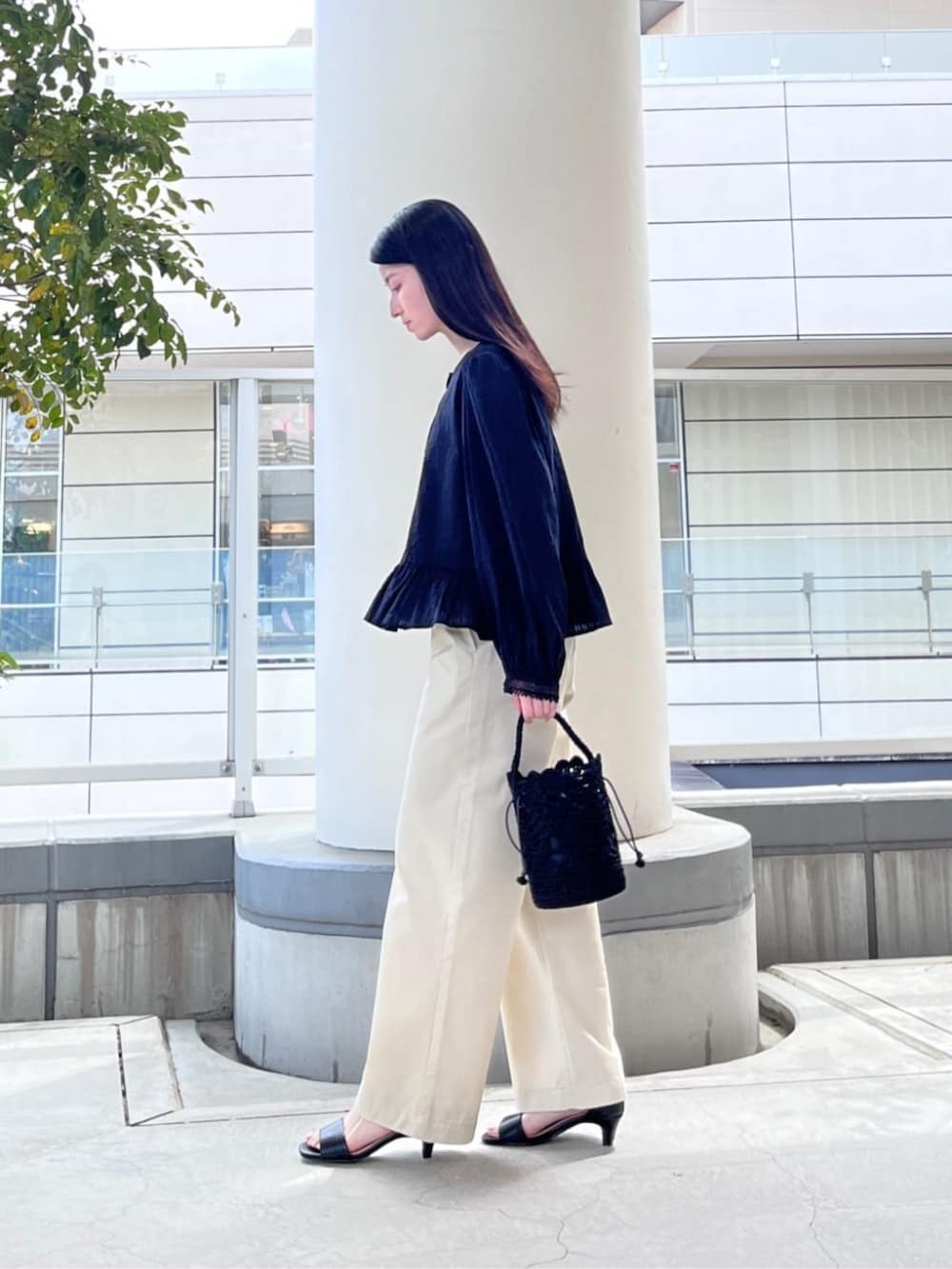 ブラック系のサンダル、ブラック系のハンドバッグ、ベージュ系のチノパンツを着用したレディースの春コーディネートの2枚目の写真