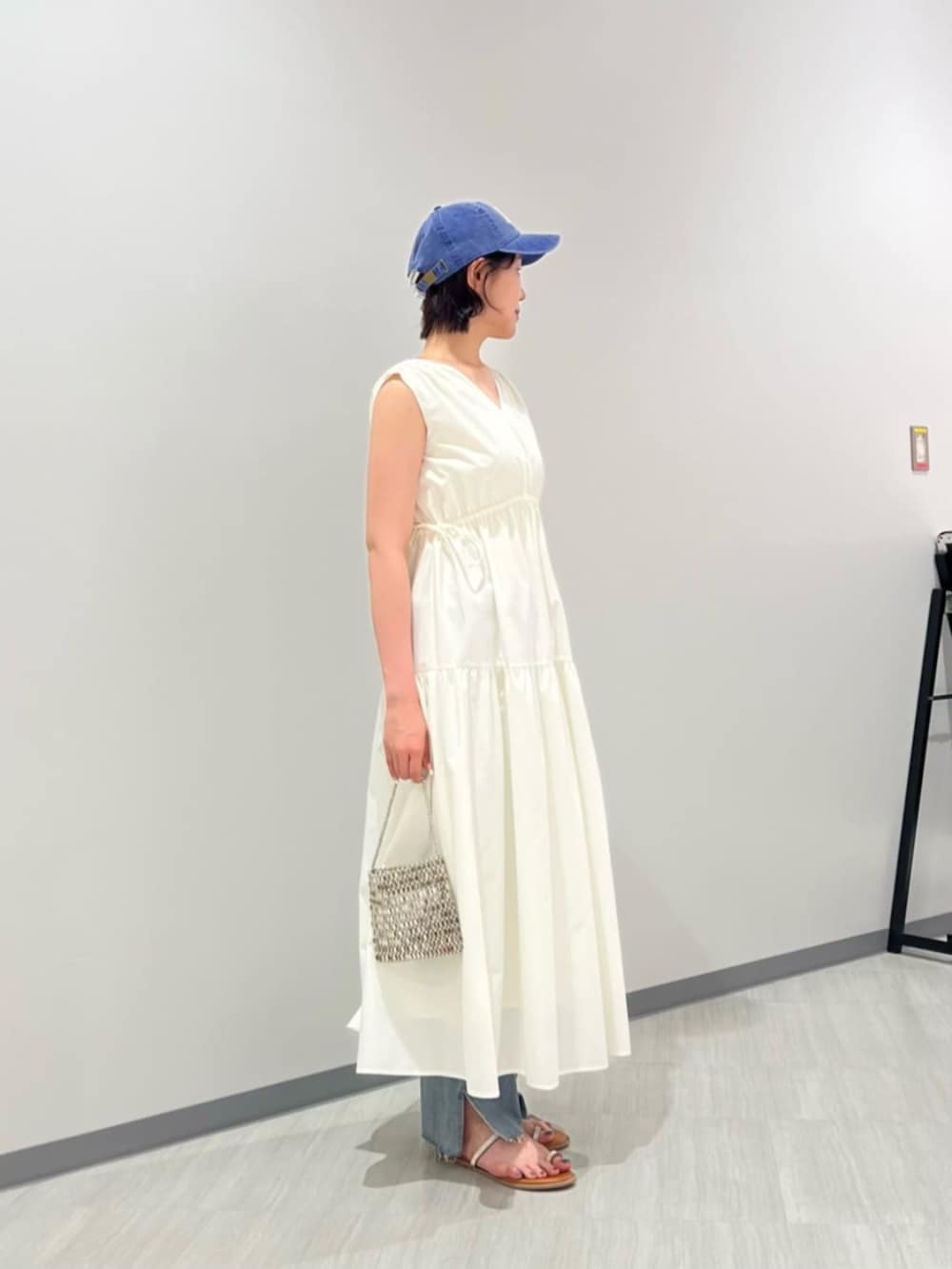 ブルー系のデニムパンツ、イエロー系のサンダル、ホワイト系のワンピースを着用したレディースの夏コーディネートの3枚目の写真