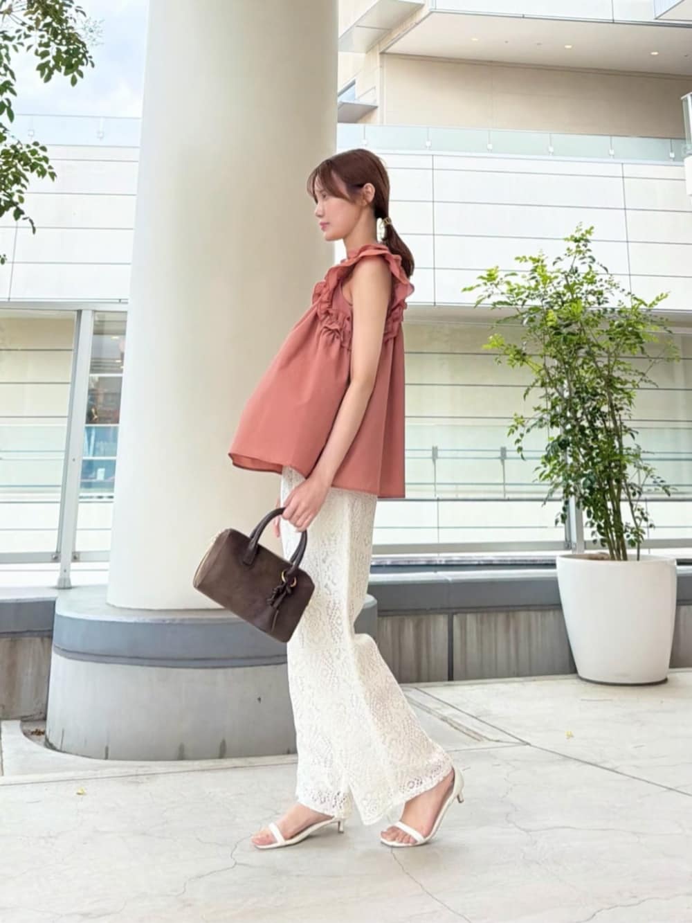 ブラウン系のボストンバッグ、ホワイト系のその他パンツ、オレンジ系のシャツ/ブラウスを着用したレディースの夏コーディネートの4枚目の写真