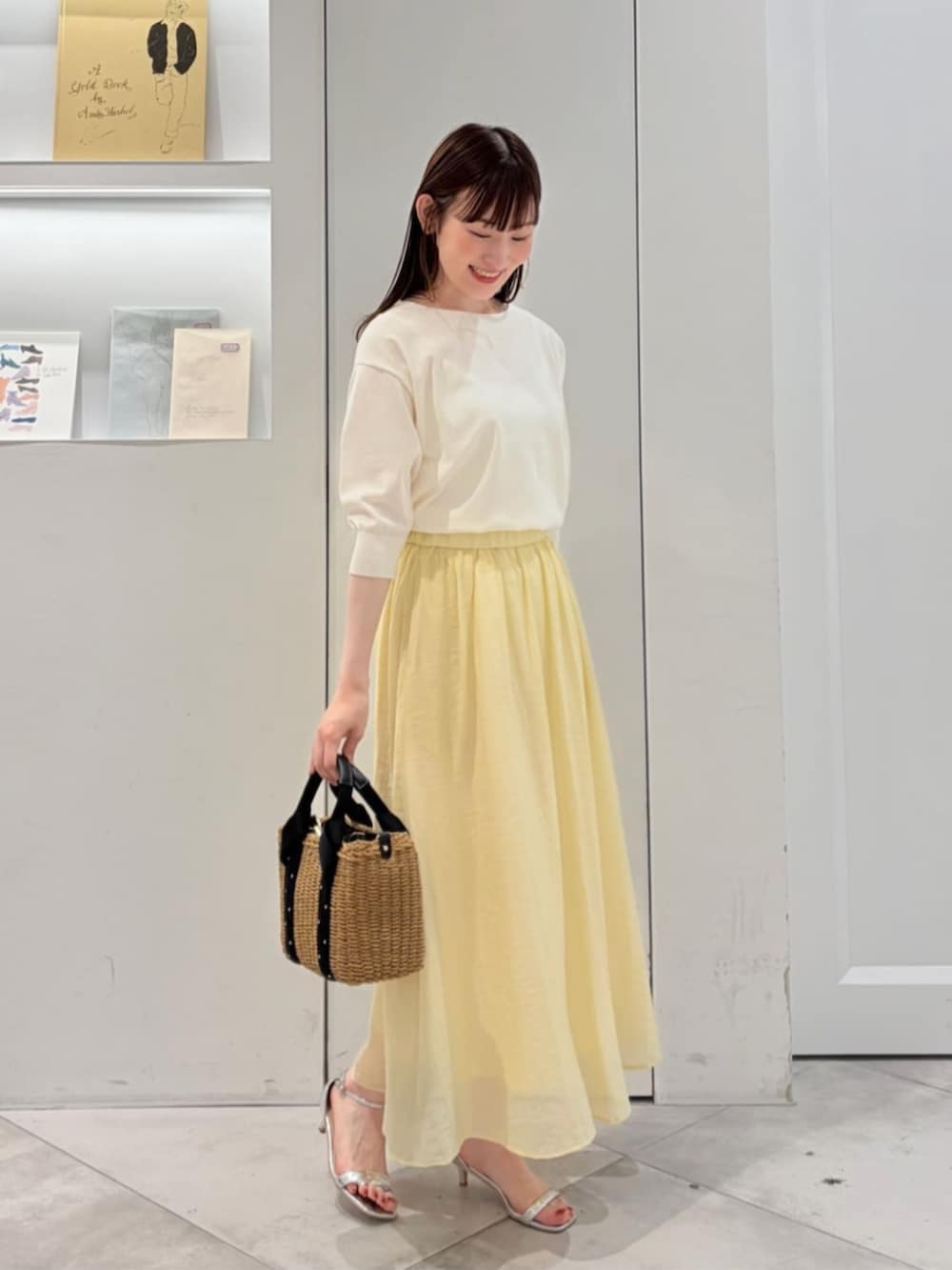 ブラック系のかごバッグ、ホワイト系のニット/セーター、イエロー系のスカートを着用したレディースの夏コーディネートの3枚目の写真