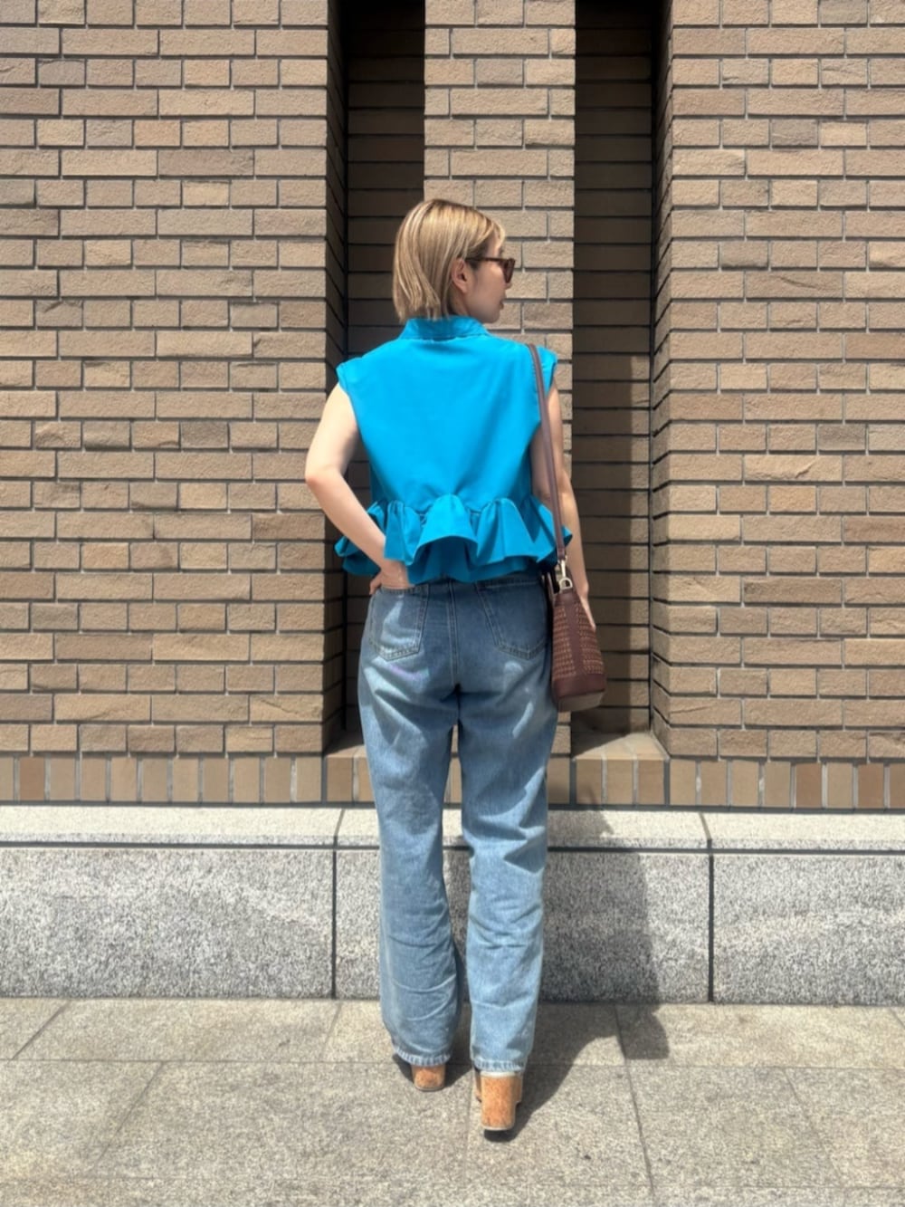 ブルー系のデニムパンツ、ブルー系のシャツ/ブラウス、オレンジ系のボストンバッグを着用したレディースの春コーディネートの4枚目の写真
