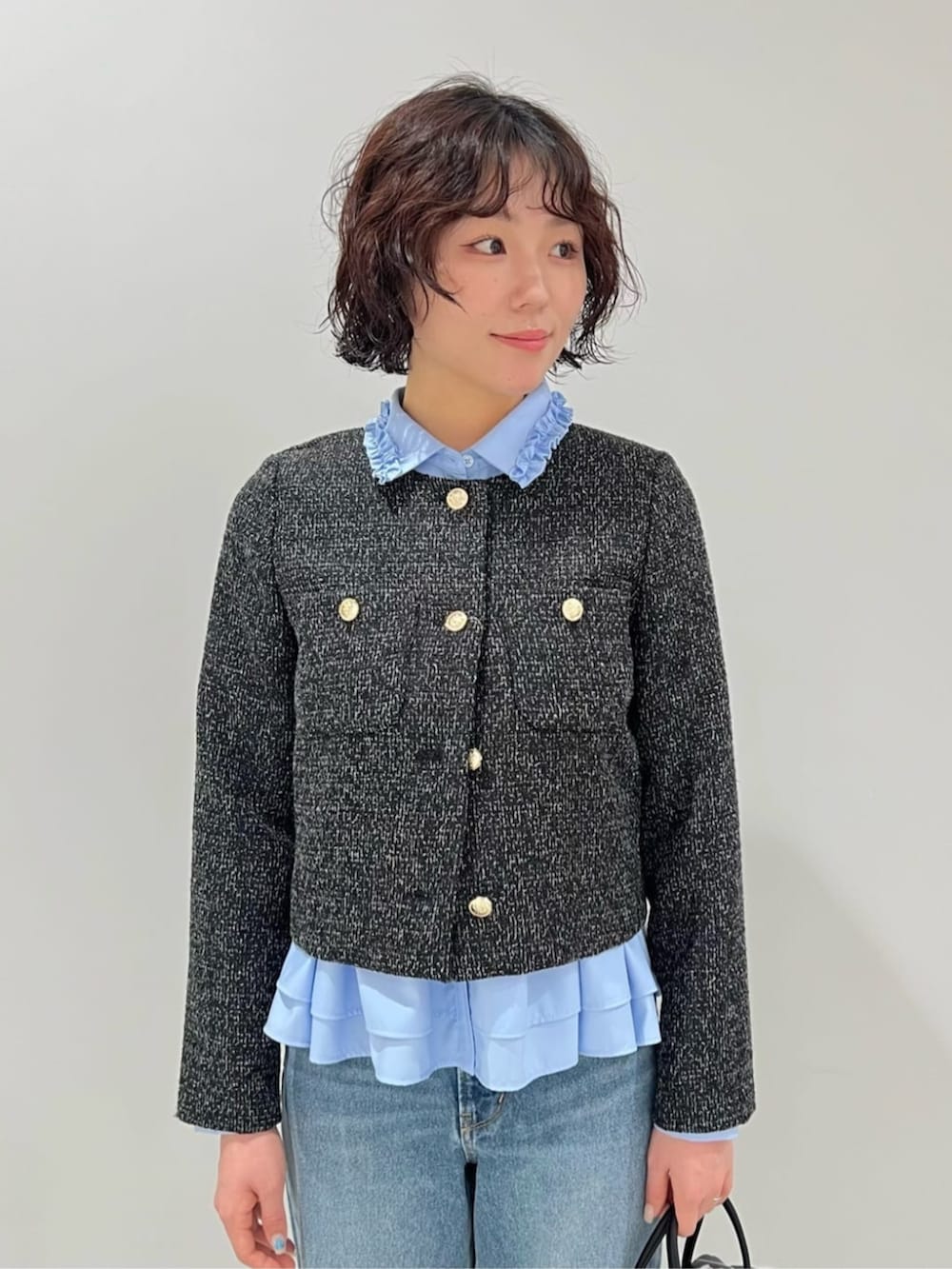 ブルー系のデニムパンツ、ブラック系のボストンバッグ、ブラック系のノーカラージャケットを着用したレディースの春コーディネートの4枚目の写真