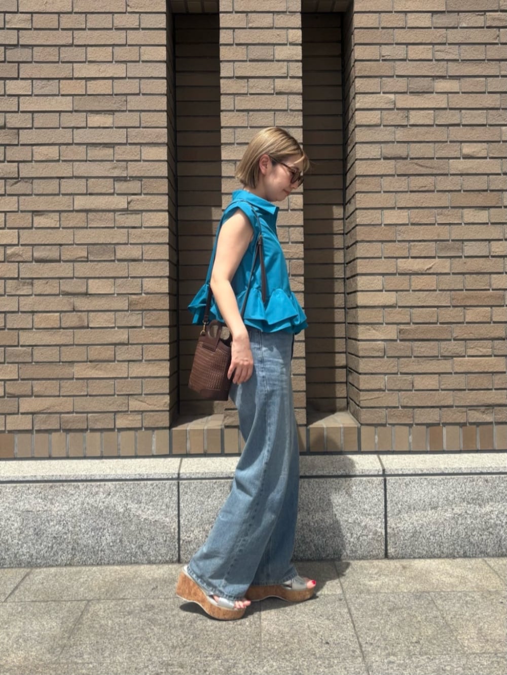 ブルー系のデニムパンツ、ブルー系のシャツ/ブラウス、オレンジ系のボストンバッグを着用したレディースの春コーディネートの3枚目の写真