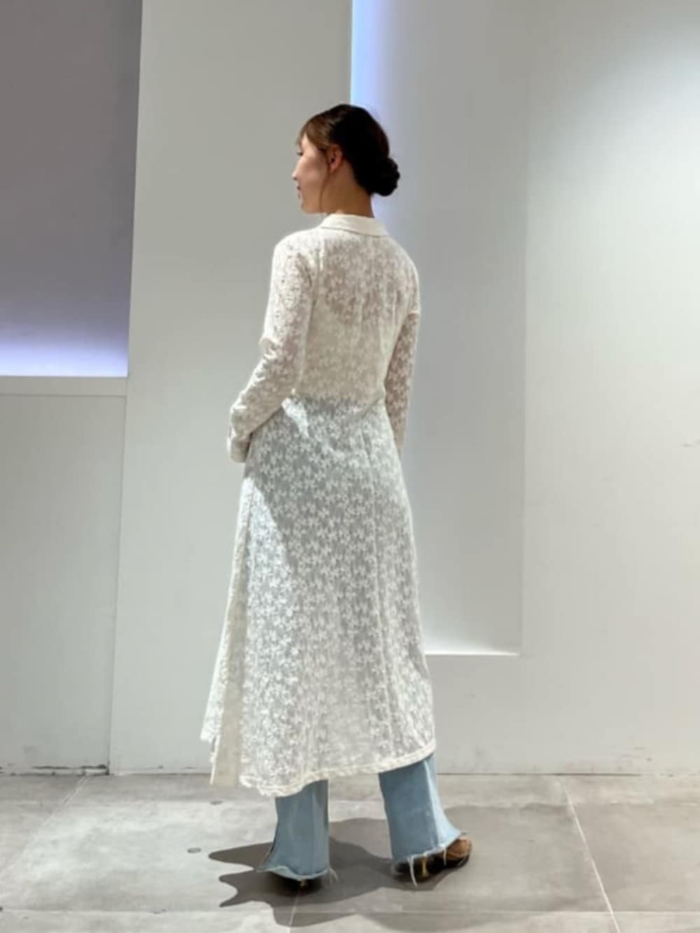 ホワイト系のシャツワンピース、ホワイト系のキャミソール、ブルー系のデニムパンツを着用したレディースの春コーディネートの3枚目の写真