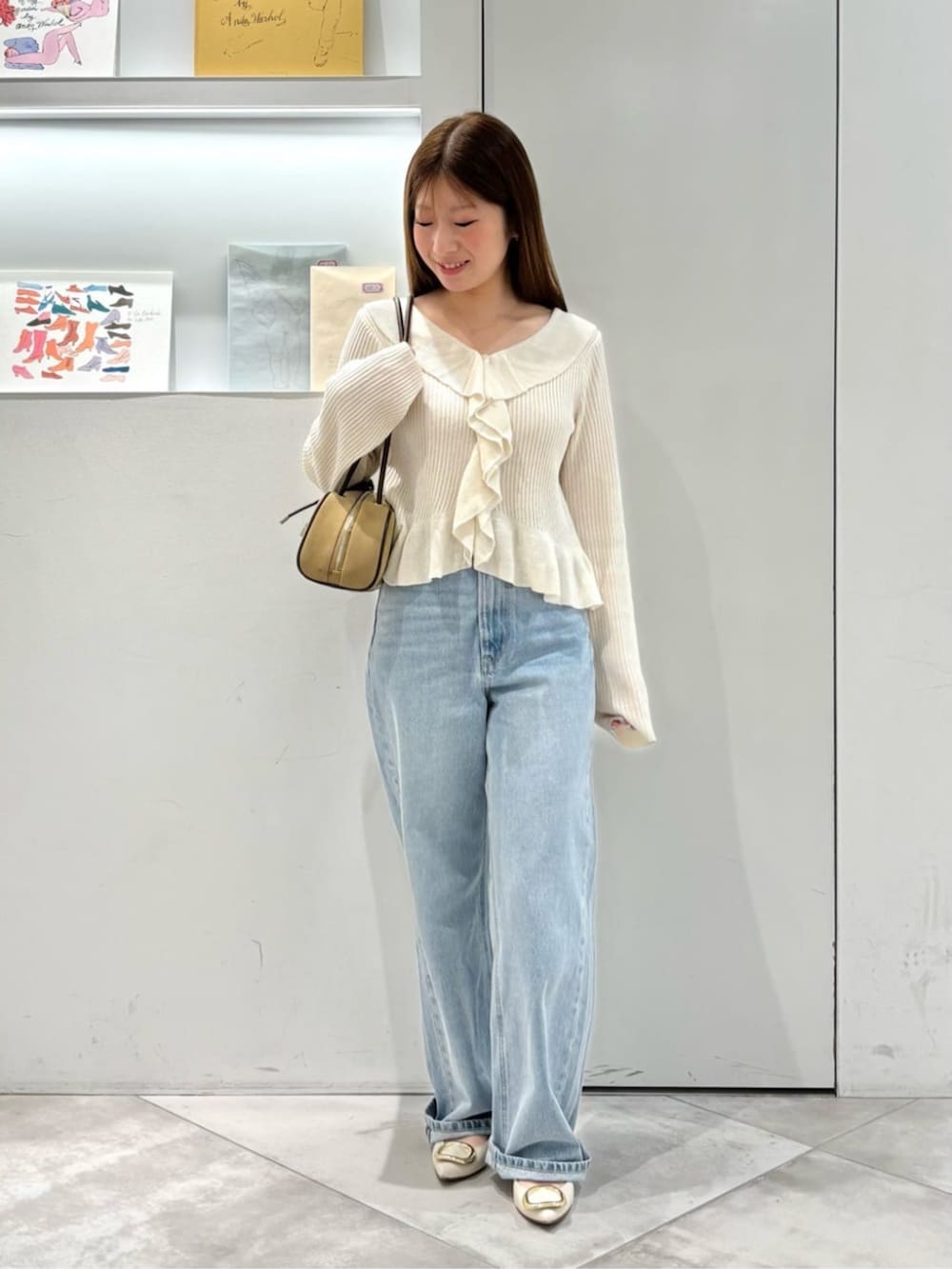 ホワイト系のカーディガン/ボレロ、ブルー系のデニムパンツ、ベージュ系のボストンバッグを着用したレディースの春コーディネートの2枚目の写真