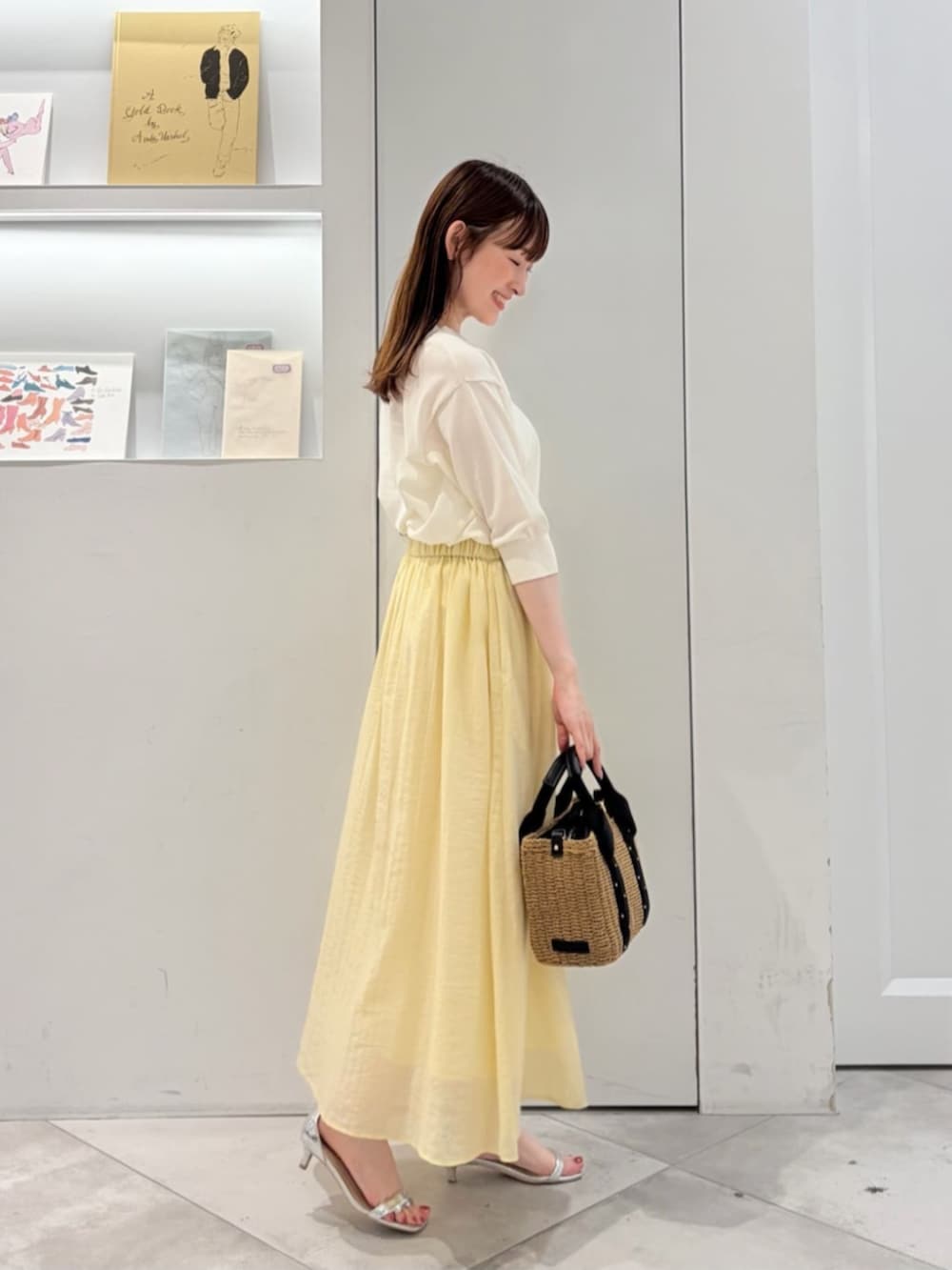 ブラック系のかごバッグ、ホワイト系のニット/セーター、イエロー系のスカートを着用したレディースの夏コーディネートの4枚目の写真