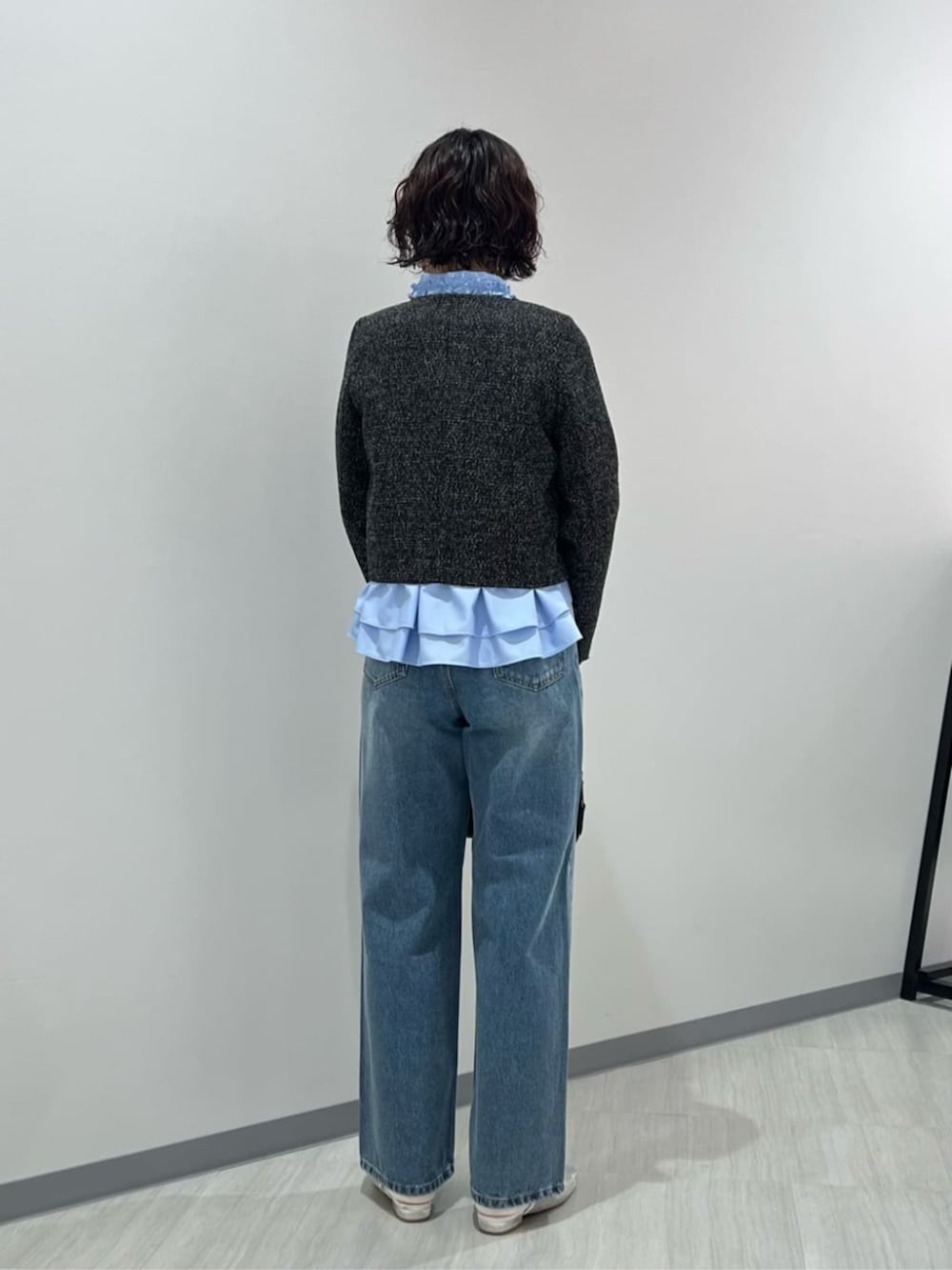 ブルー系のデニムパンツ、ブラック系のボストンバッグ、ブラック系のノーカラージャケットを着用したレディースの春コーディネートの3枚目の写真