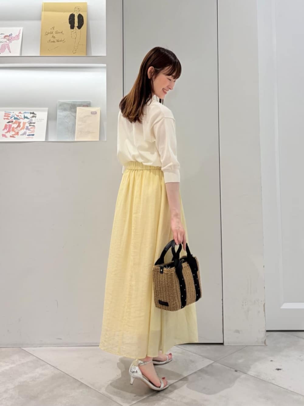 ブラック系のかごバッグ、ホワイト系のニット/セーター、イエロー系のスカートを着用したレディースの夏コーディネートの5枚目の写真